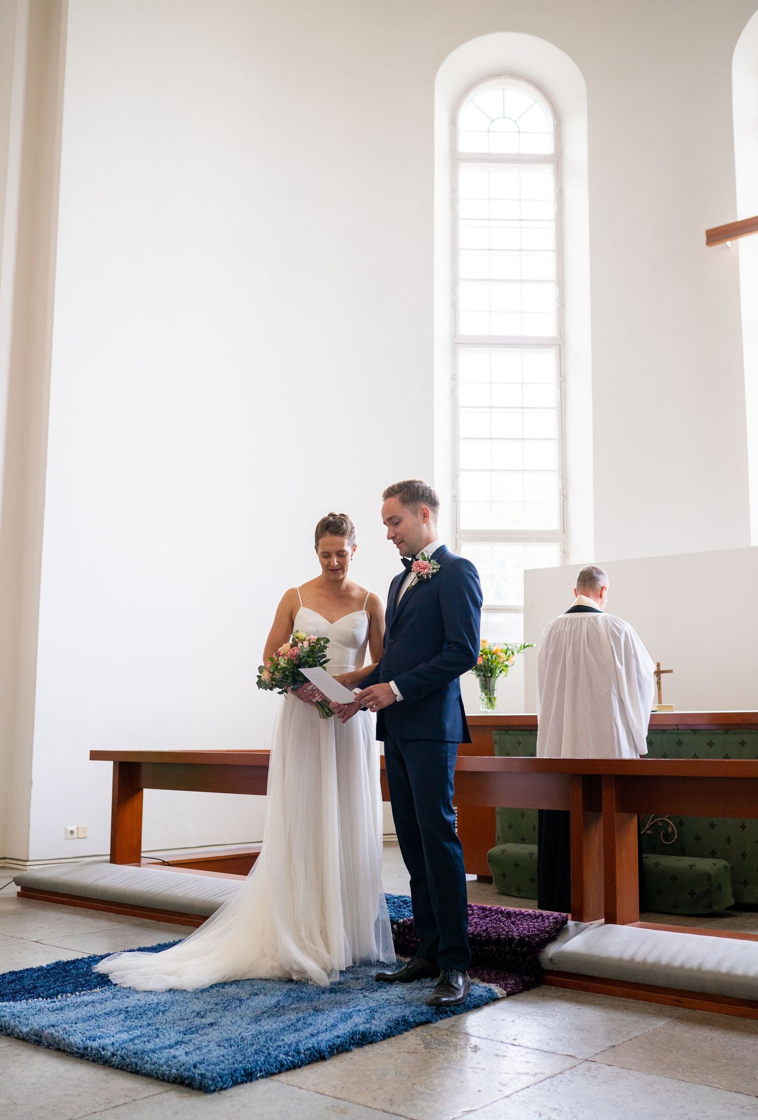 Bride and groom reading vows together at church altar during wedding ceremony.