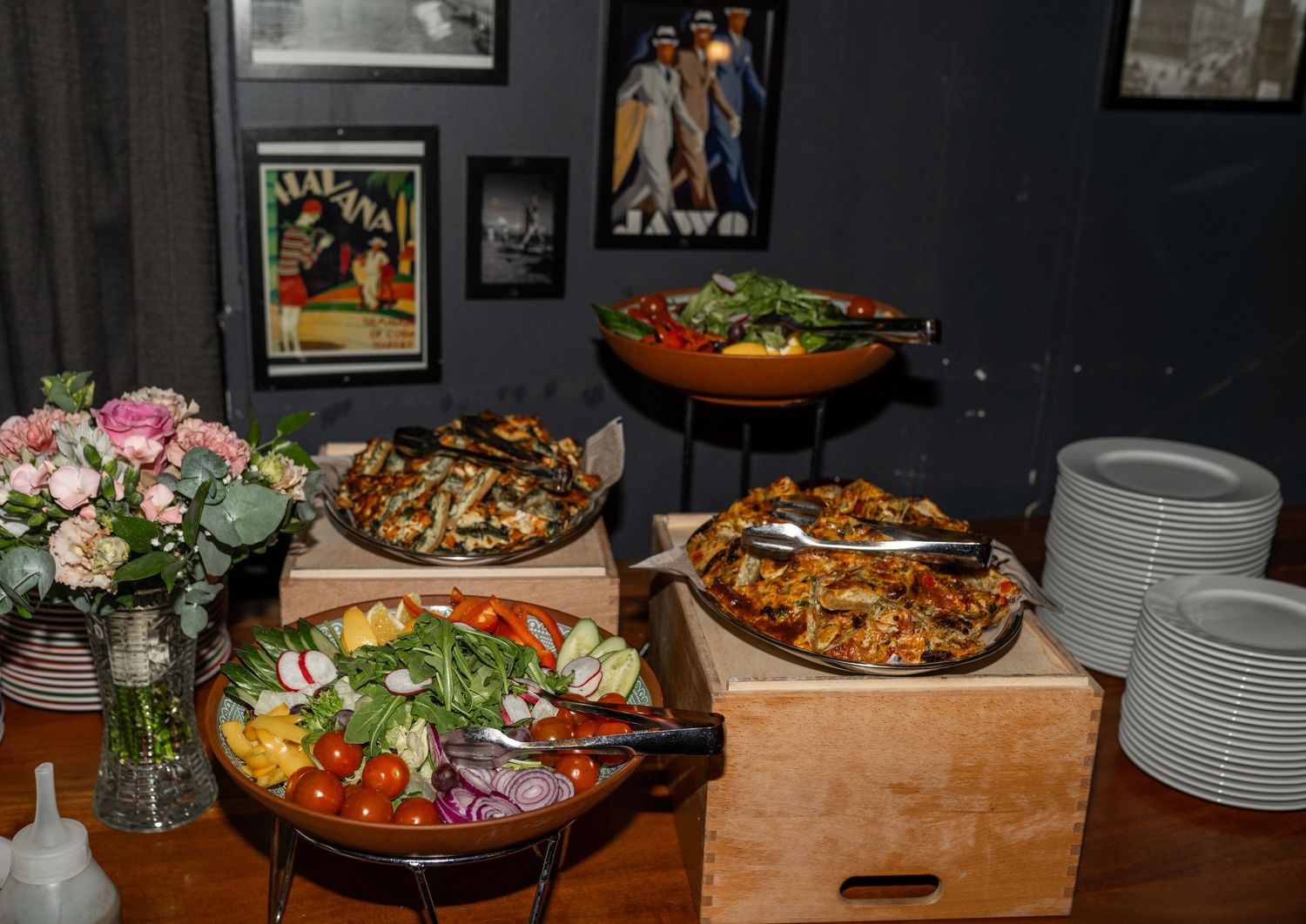 Elegant wedding reception buffet with colorful salads and dishes displayed on wooden table with florals.