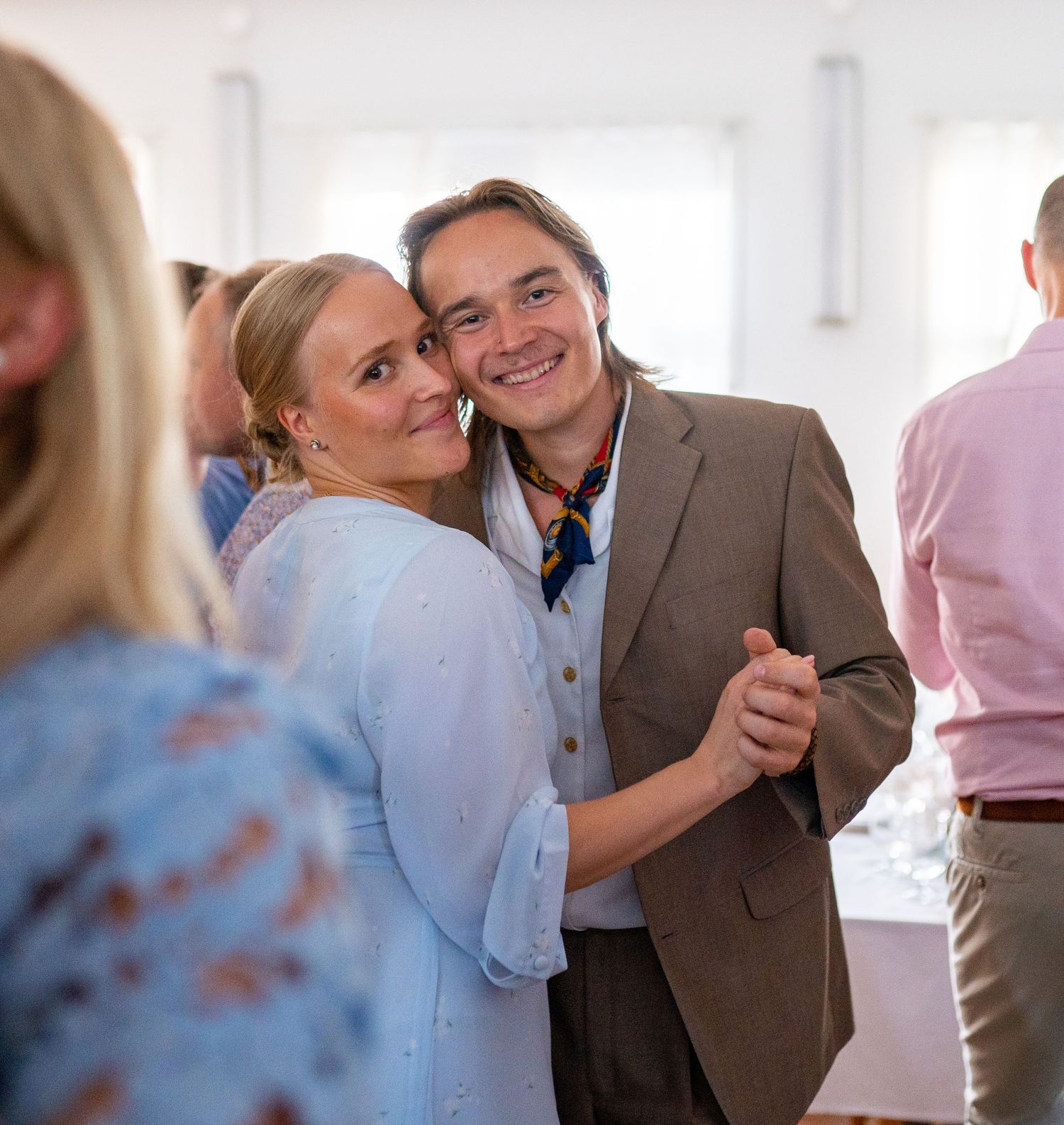 Smiling couple dancing closely together at elegant wedding reception, woman in light blue floral dress.