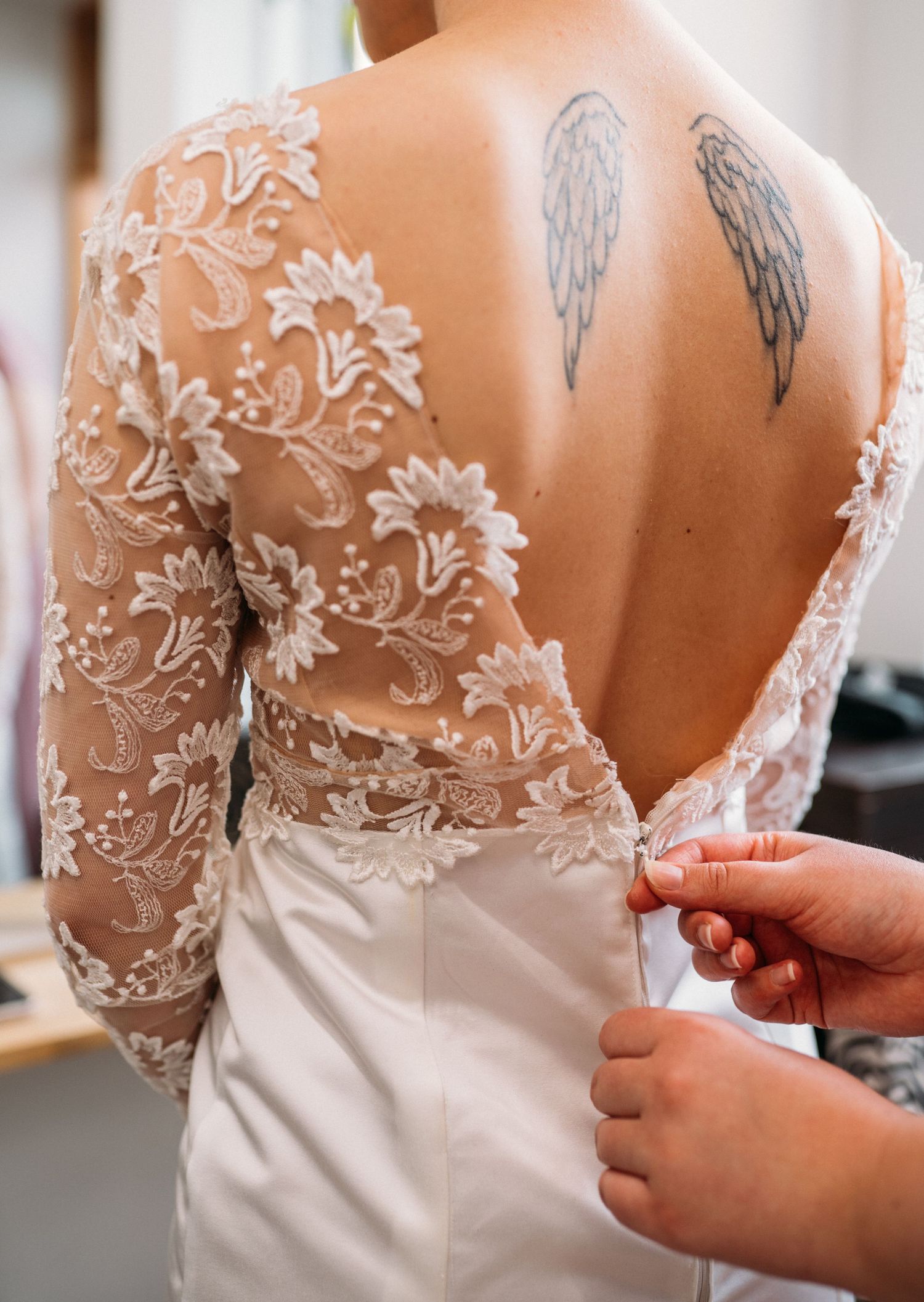 Close-up of intricate lace back wedding gown with angel wings tattoo on brides upper back.