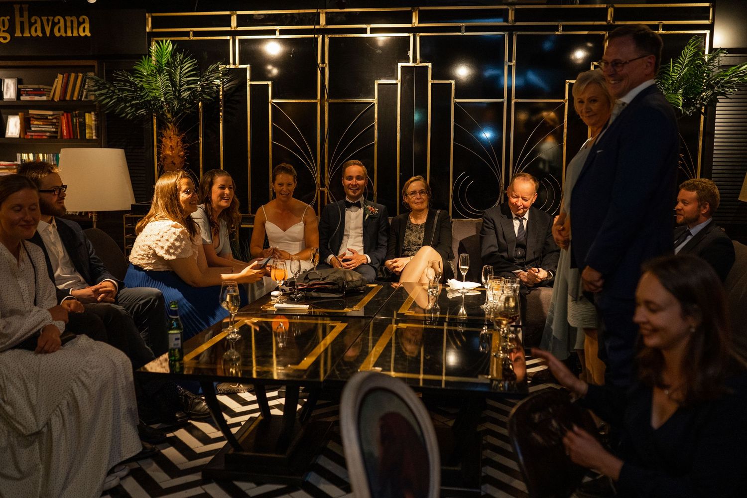 Wedding guests laughing and socializing around glass table at Trading Havana venue.