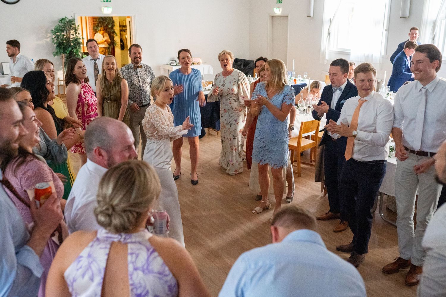 Wedding guests mingle and celebrate together in a bright elegant reception hall during the festivities.