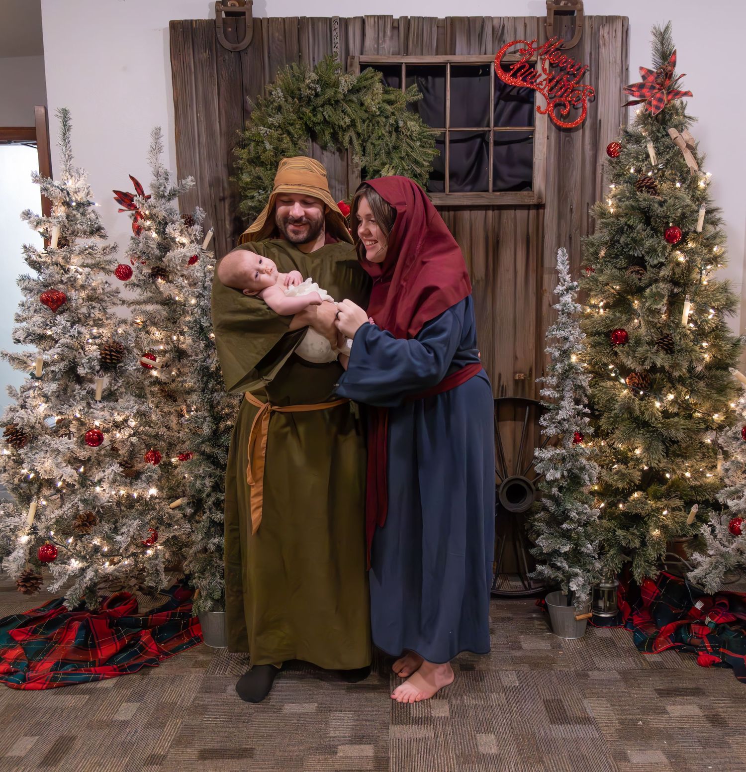 Christmas scene with couple in biblical costumes between decorated trees.
