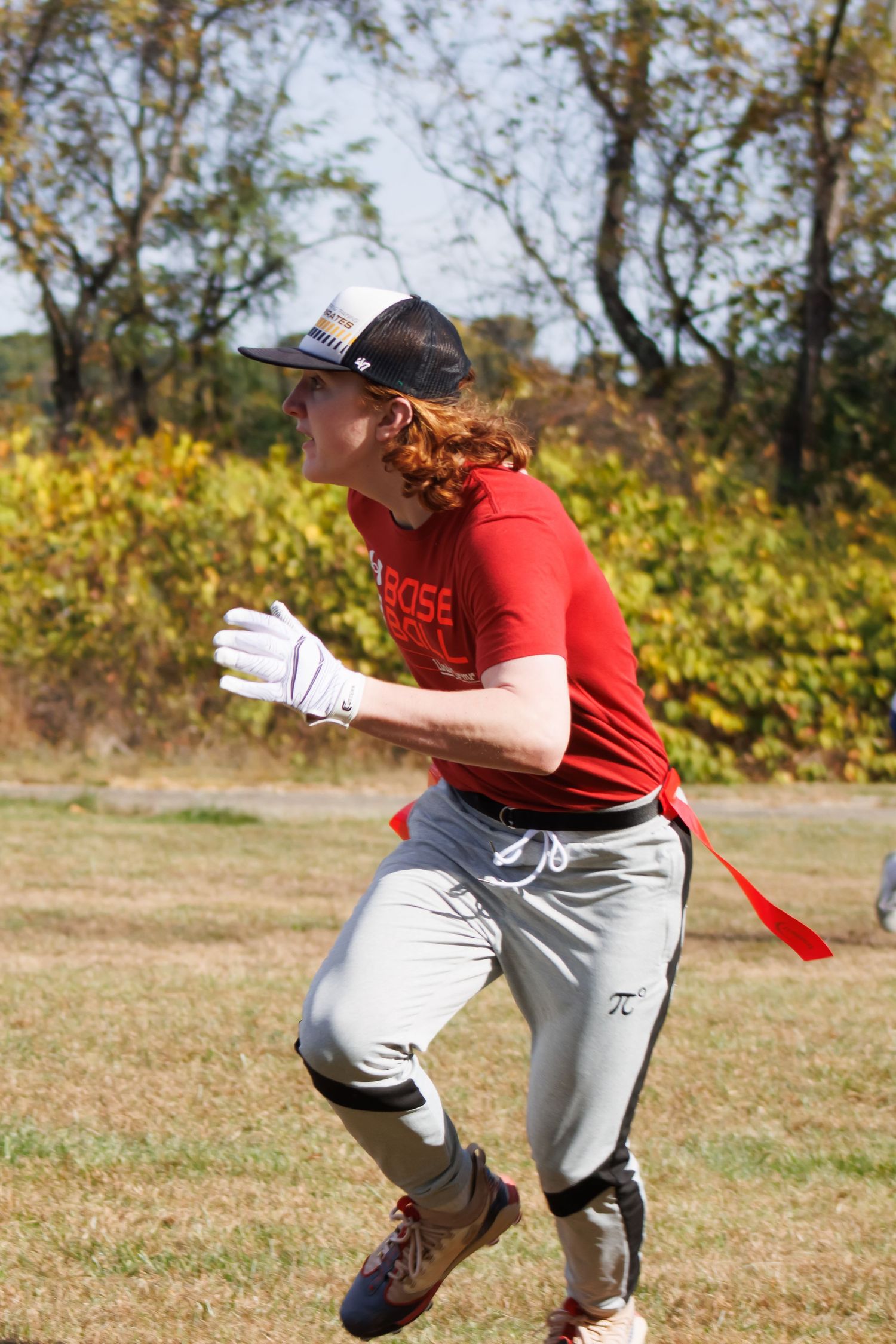 Player in red shirt and gray pants practicing athletic movements outdoors.