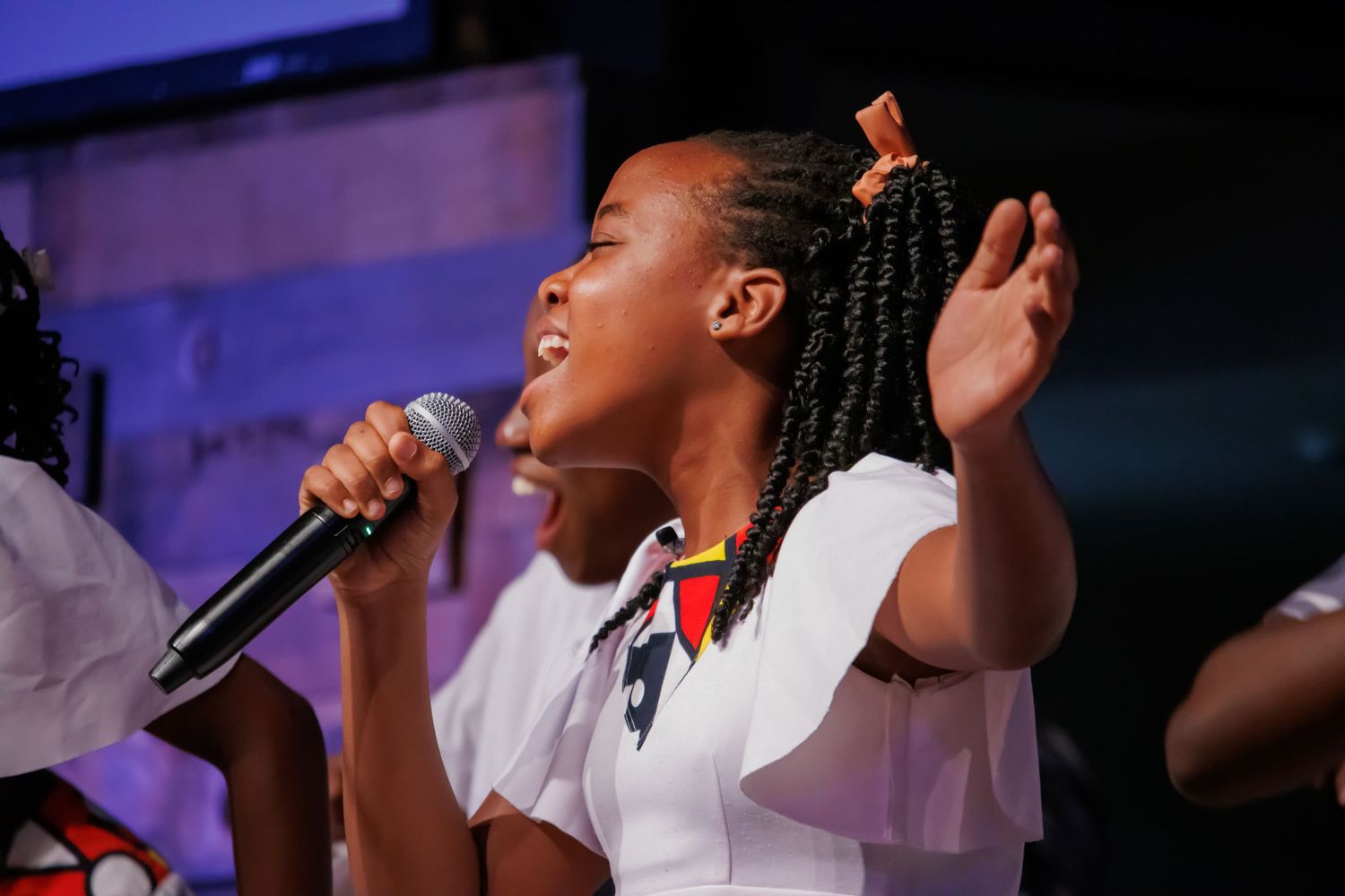 Choir members performing with microphones under blue stage lighting.
