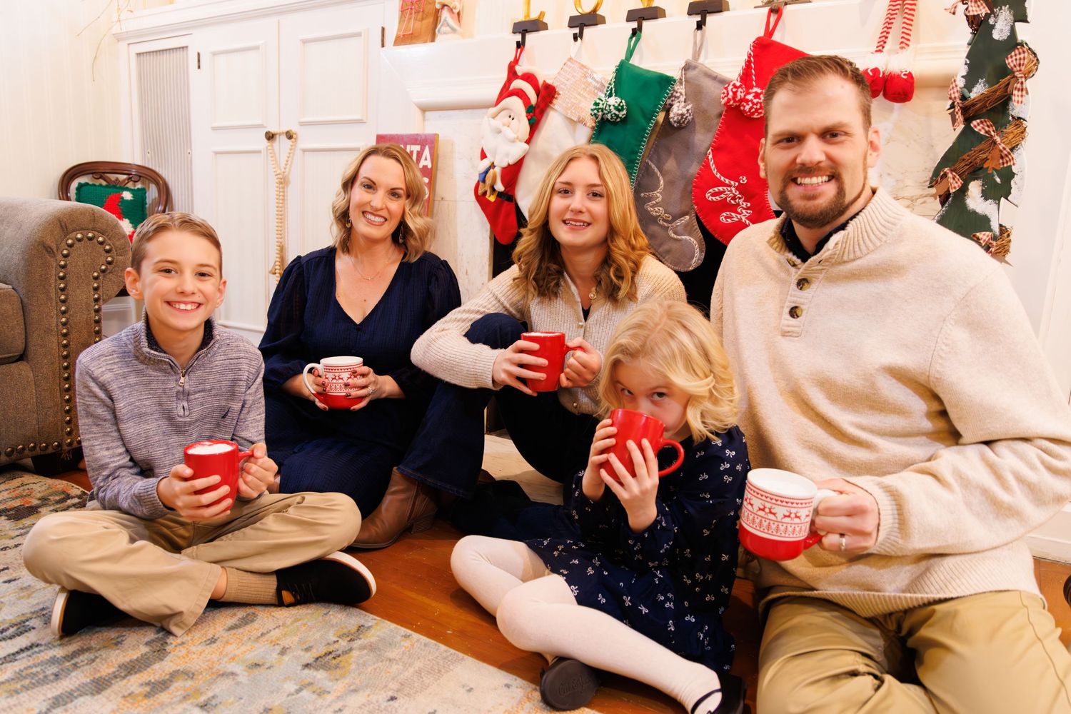 Holiday decorations with stockings and garland hanging on white wall.