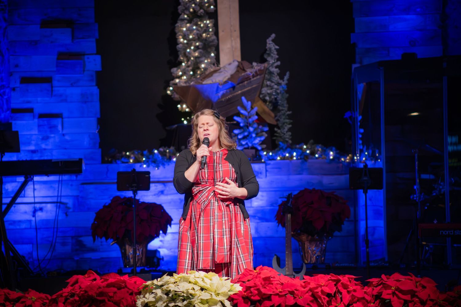 A stage decorated with blue lighting and Christmas decorations featuring a harp performance.