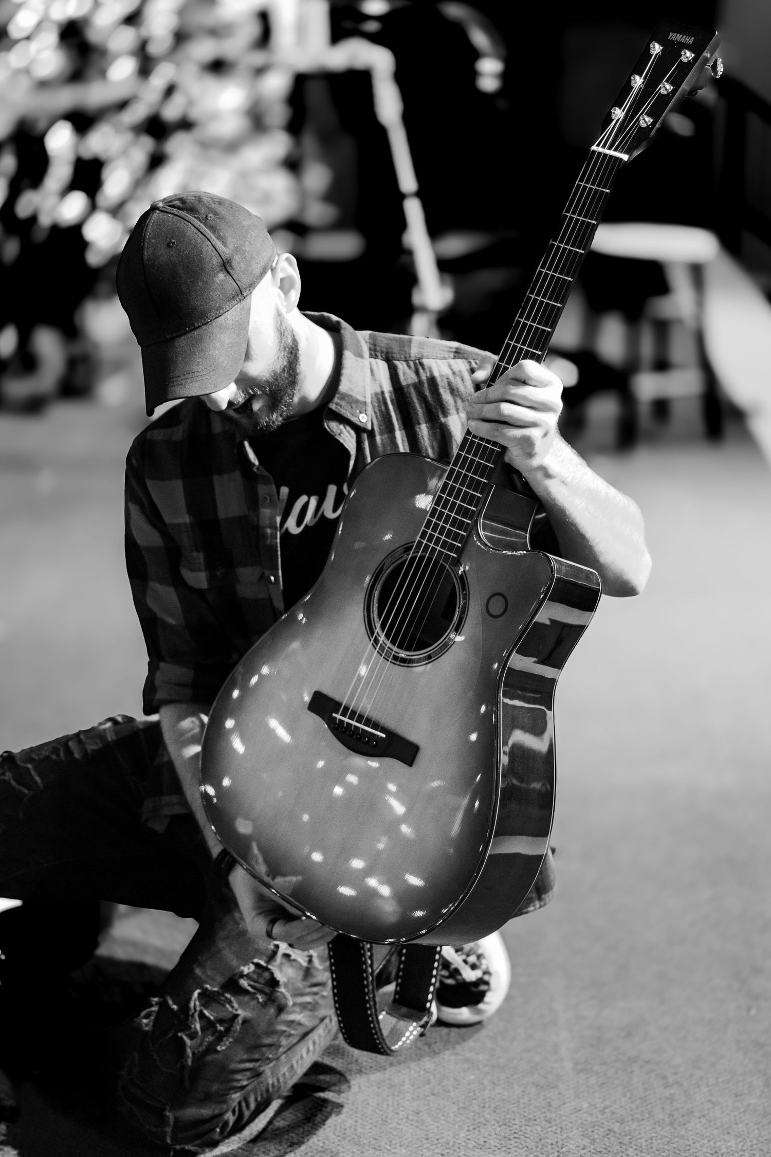 Close-up of acoustic guitar with twinkling lights creating bokeh effect in black and white.