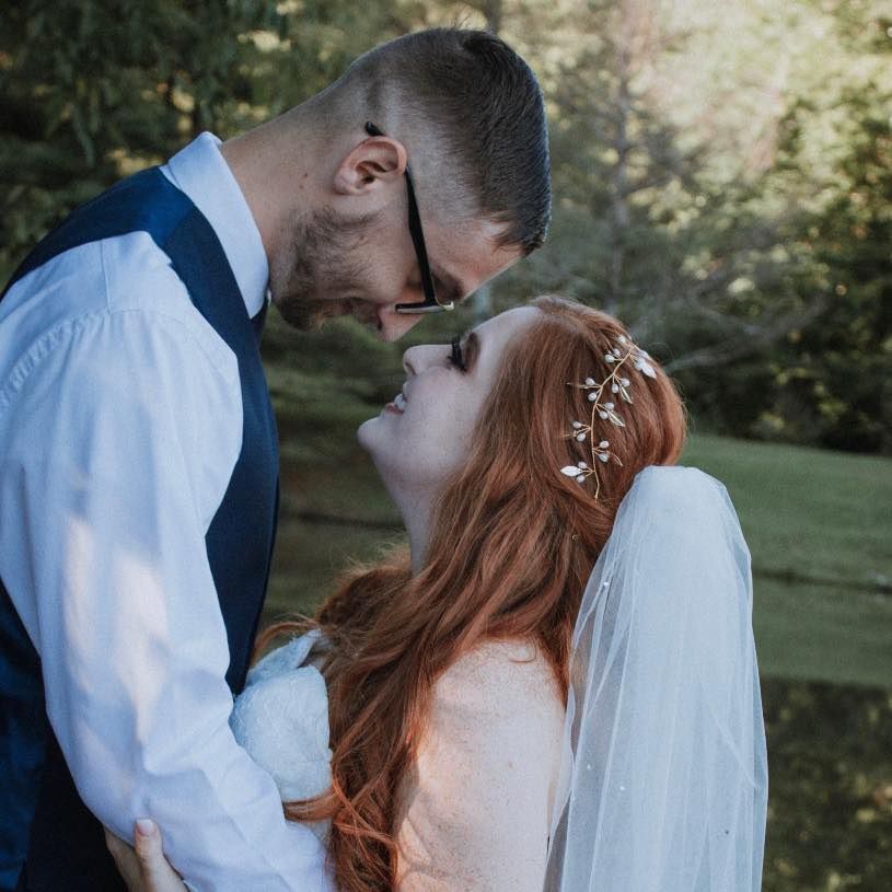 Romantic outdoor wedding photo showing couple embracing in a garden setting.