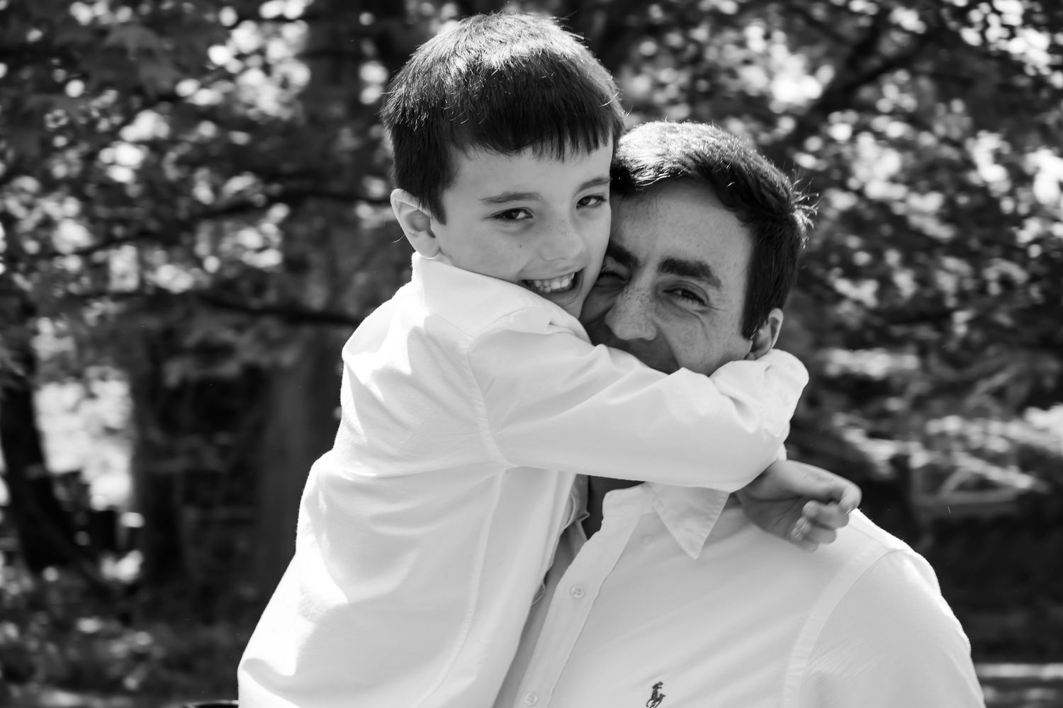 Black and white photo of father and son embracing outdoors.