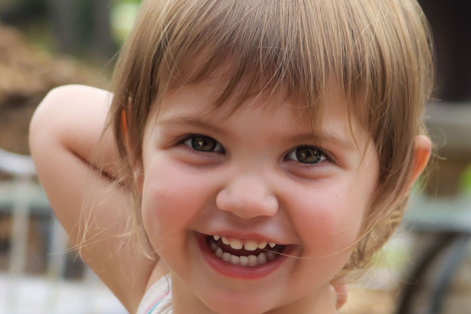 A close-up portrait showing a bright smile and playful expression against a dark background.