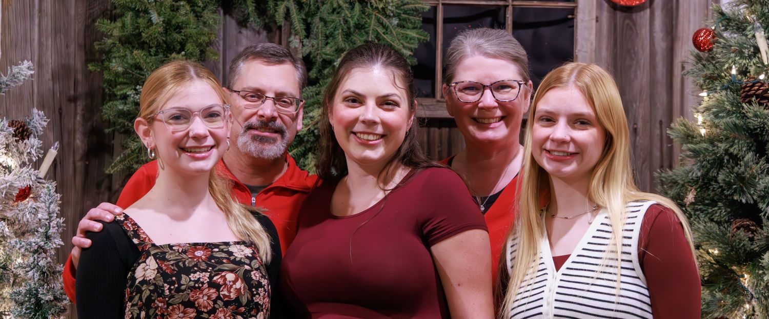 A group photo of people wearing coordinated burgundy and red holiday outfits.