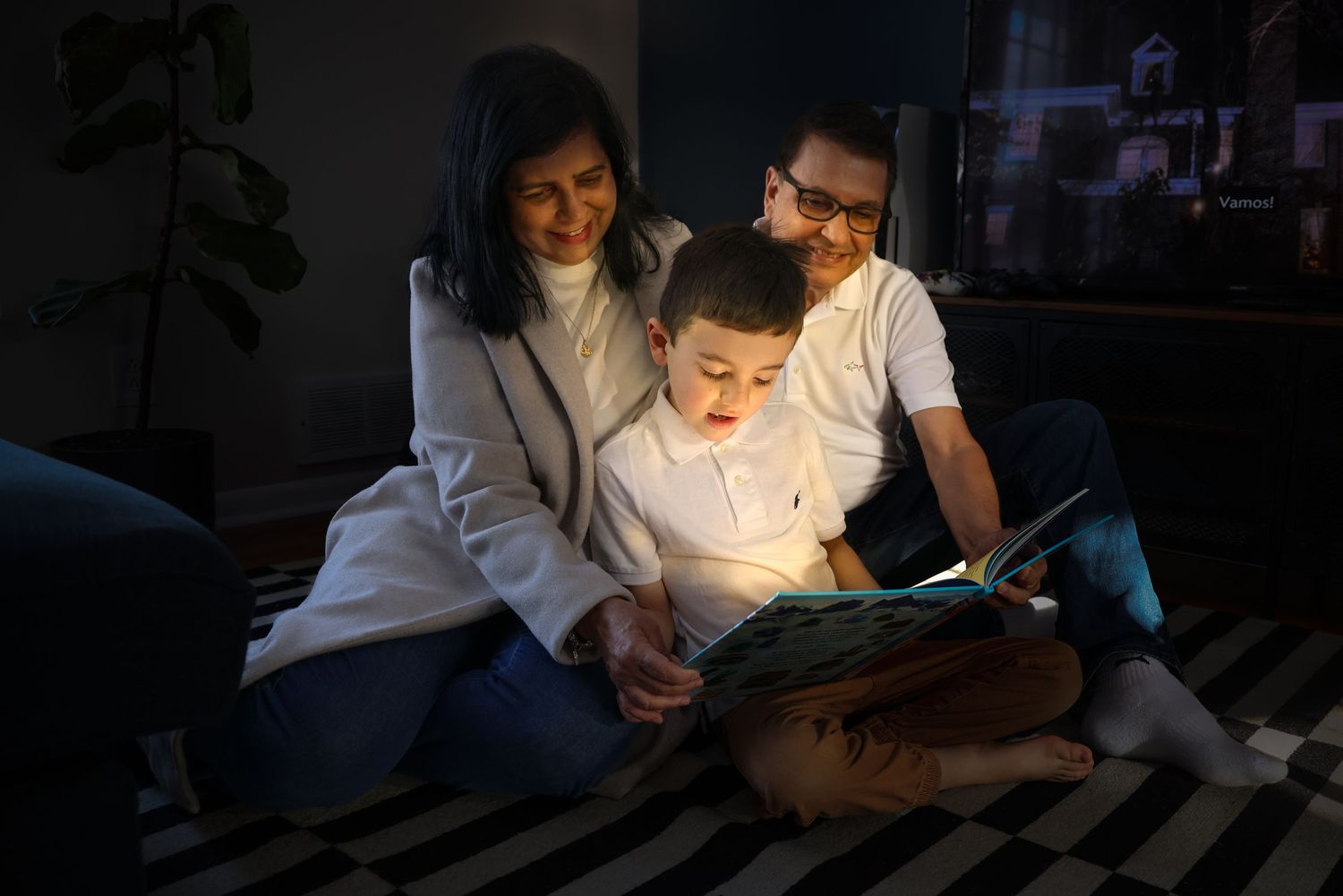 Family reading together in dim lighting on a comfortable couch.