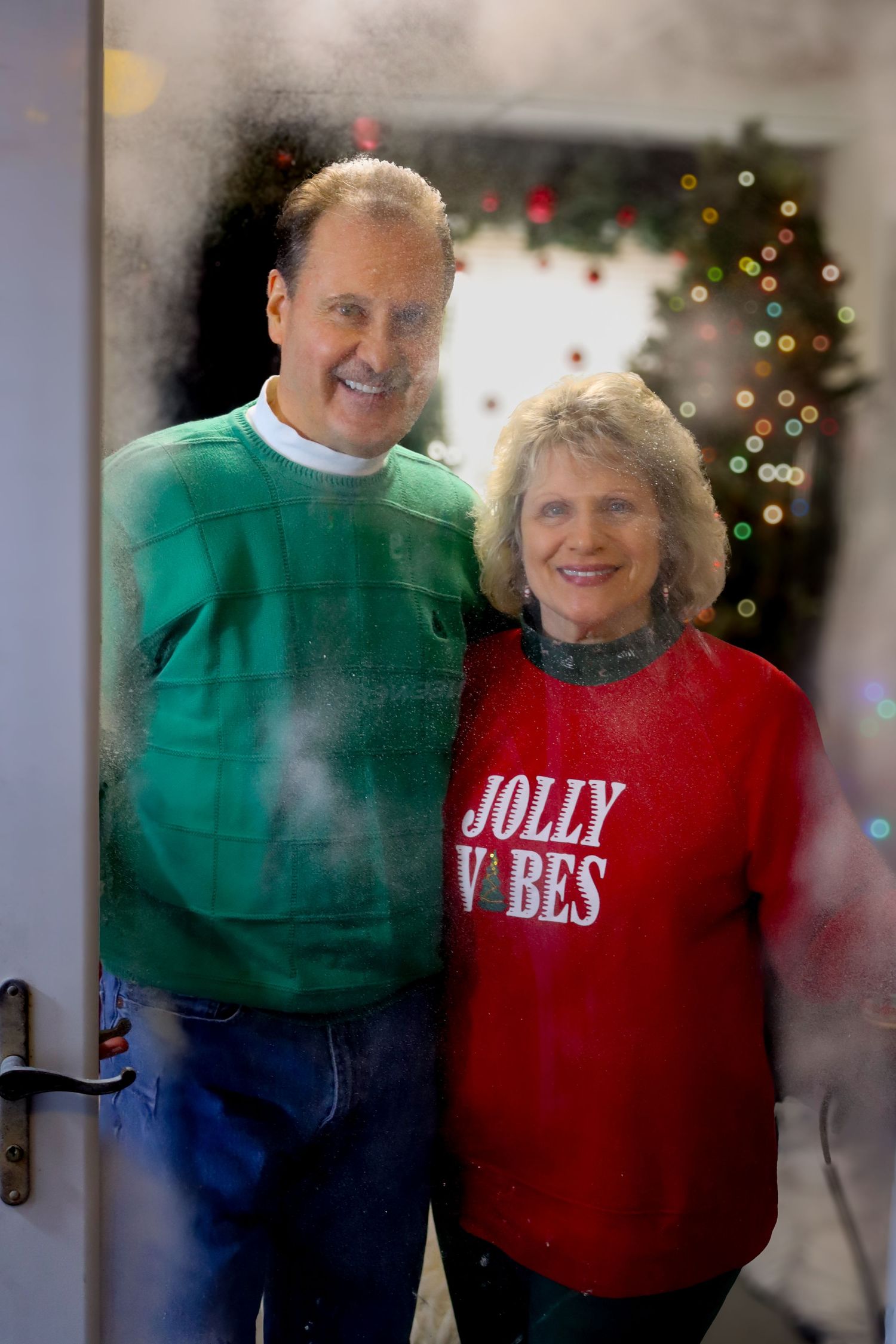 A festive holiday portrait with people wearing red and green sweaters in front of Christmas decorations.