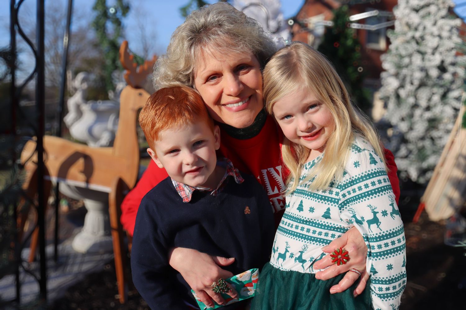 A cheerful outdoor family portrait during winter with snow-covered trees in the background.