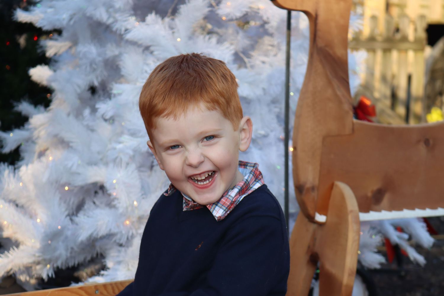 A joyful moment captured in front of a snow-covered Christmas tree display.