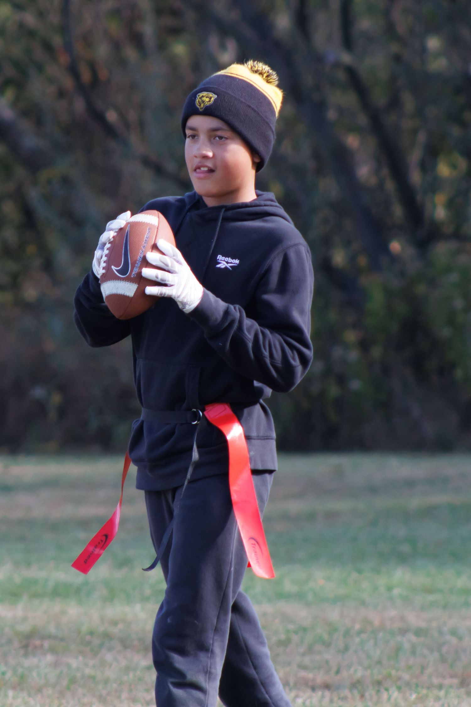 A flag football player in winter gear practicing ball handling drills.