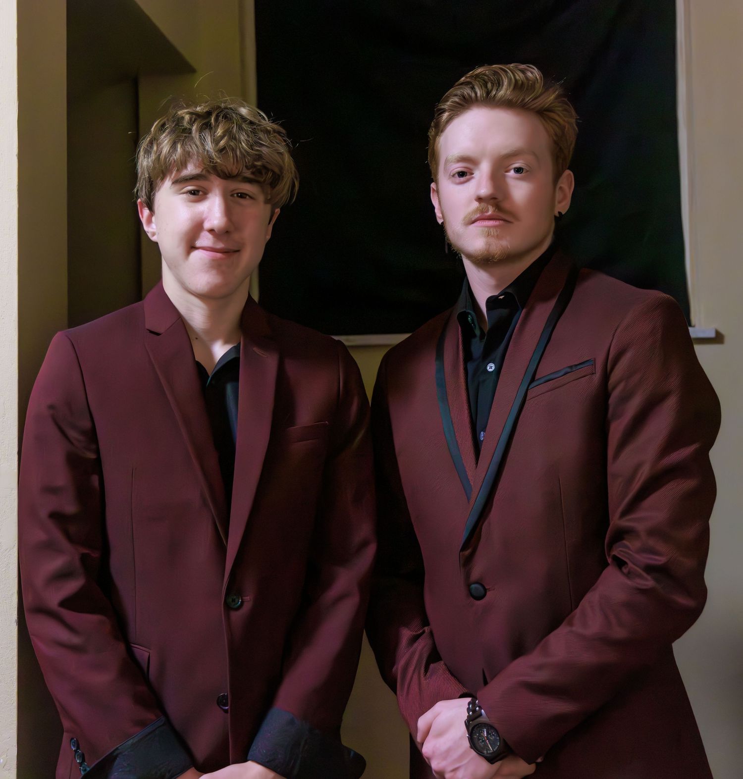 Young men in matching burgundy suits pose for a formal group photo.