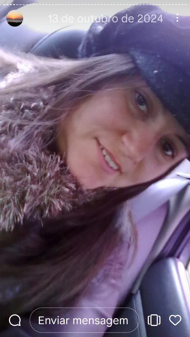 Close-up selfie showing long brown hair and a black hat taken from inside a car.