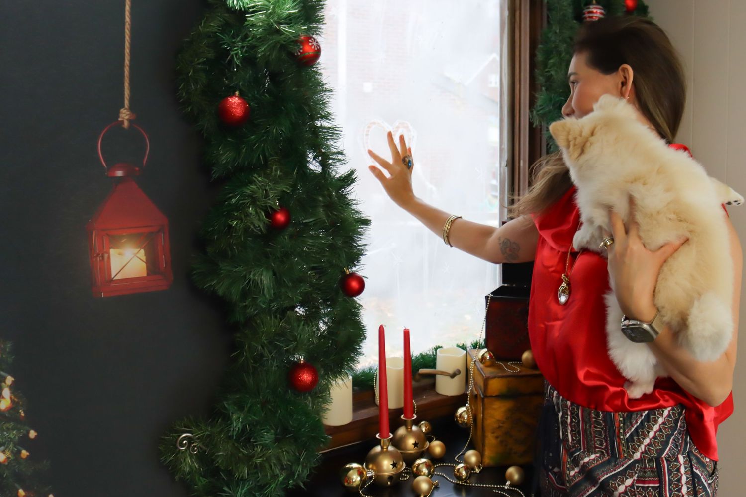 Holiday decorated window with red ornaments and evergreen wreath.
