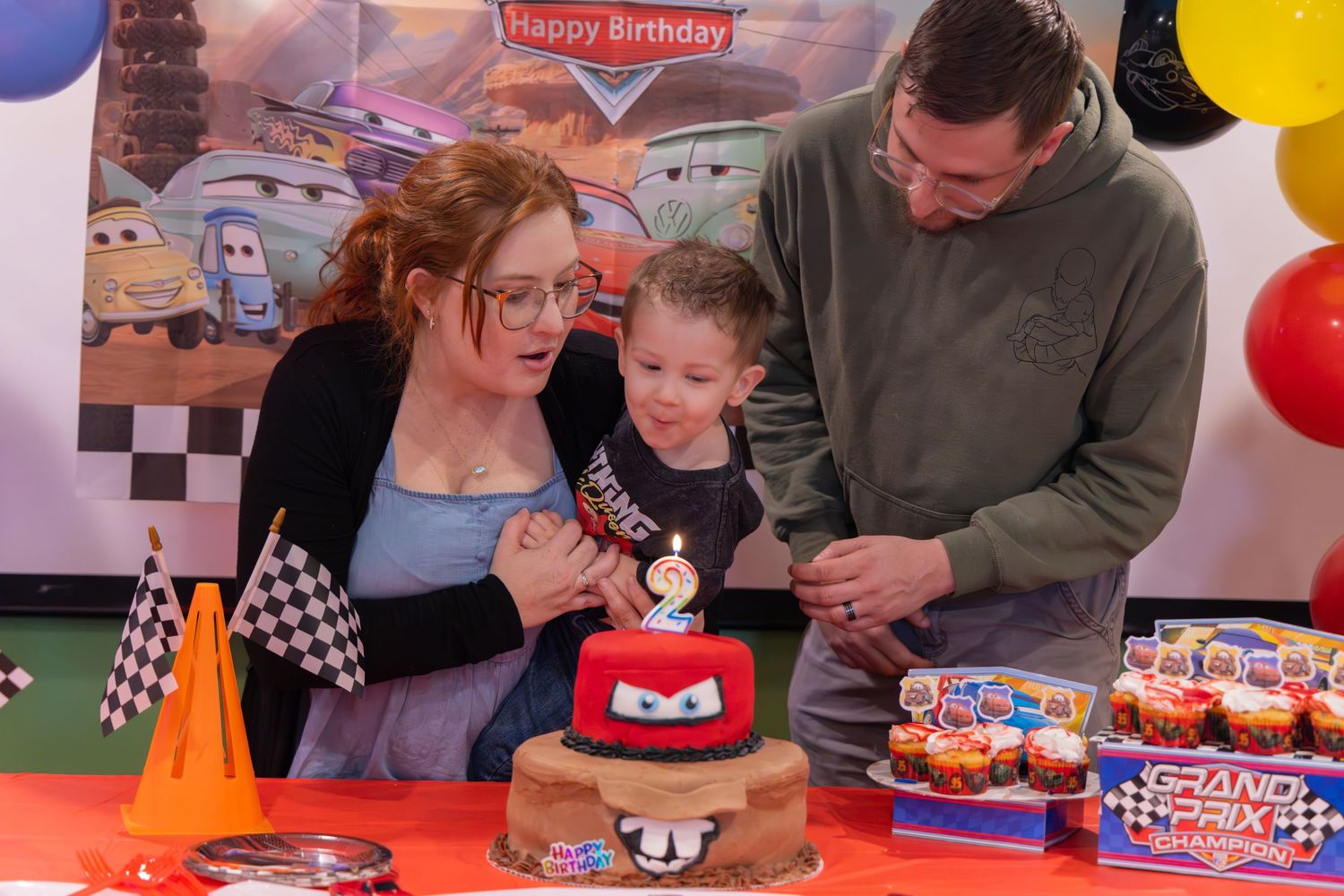 Cars themed birthday party decorations with checkered flags and colorful balloons.