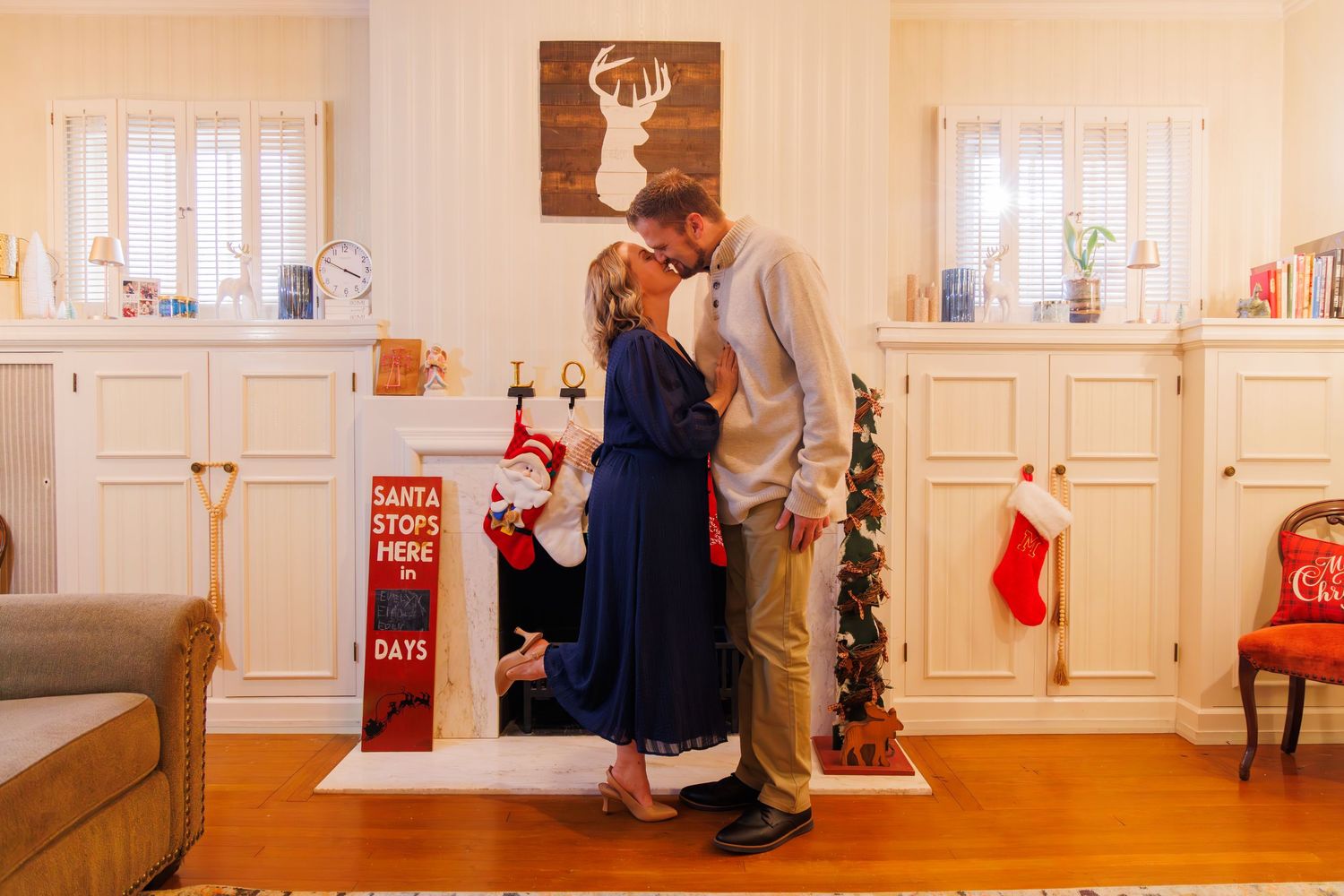 Bright interior room decorated for Christmas with stockings and deer artwork on wall.