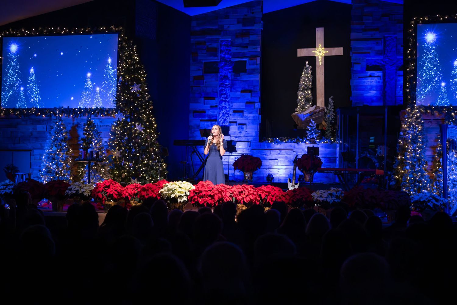 Church Christmas service with cross and trees illuminated in blue light.