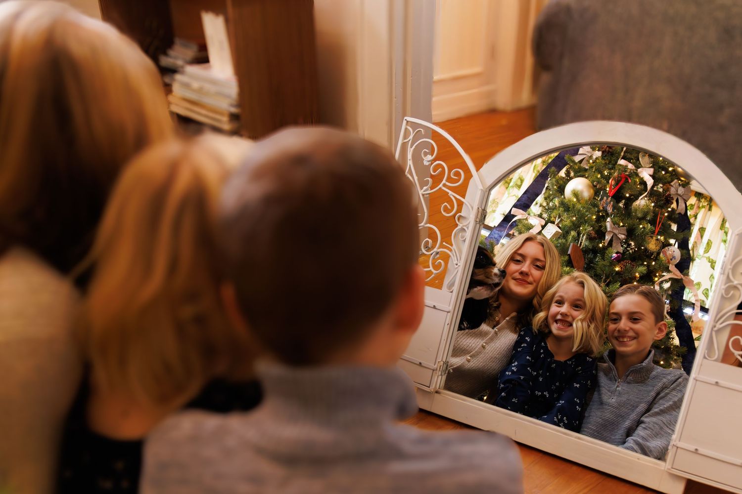 People enjoying holiday festivities in a warmly lit room with Christmas decorations.