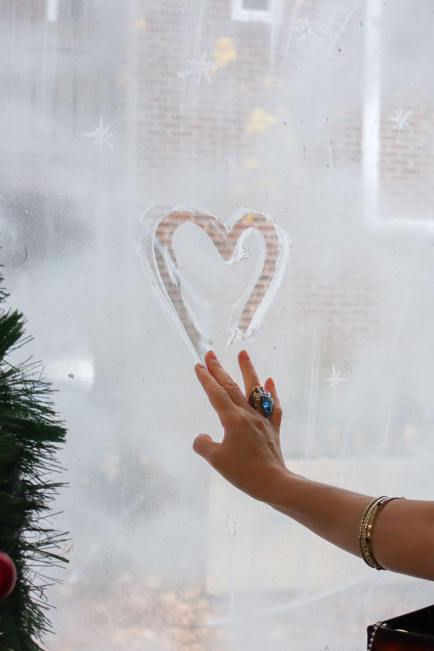 Hand drawing a heart shape on a foggy window during winter.