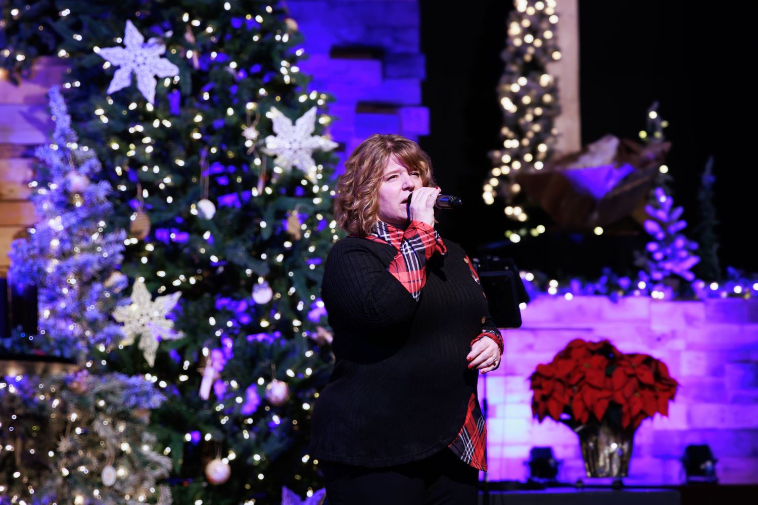 Christmas lights and decorations illuminate a stage with purple and blue lighting effects.