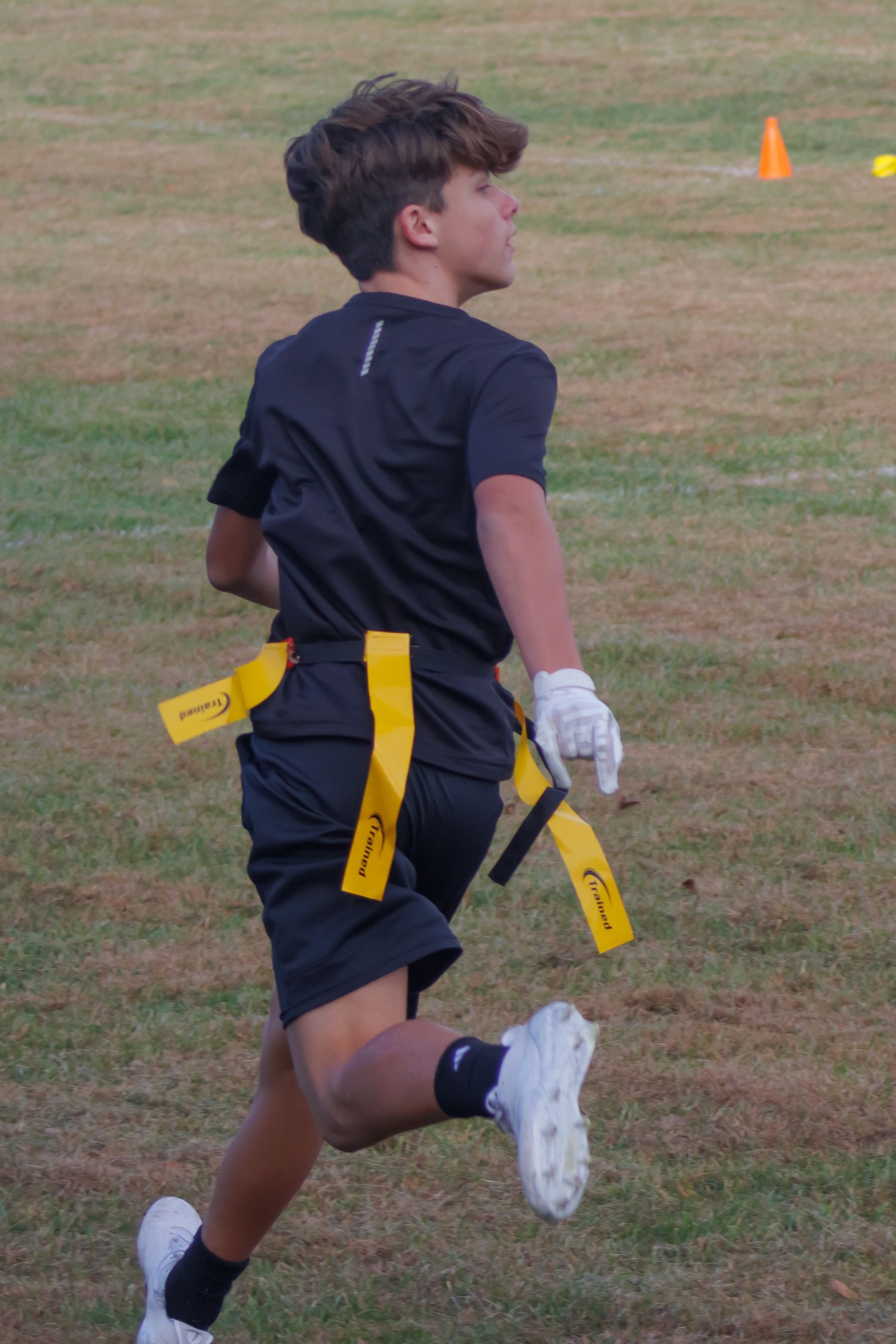 A player practicing flag football maneuvers wearing black shorts with yellow flags.