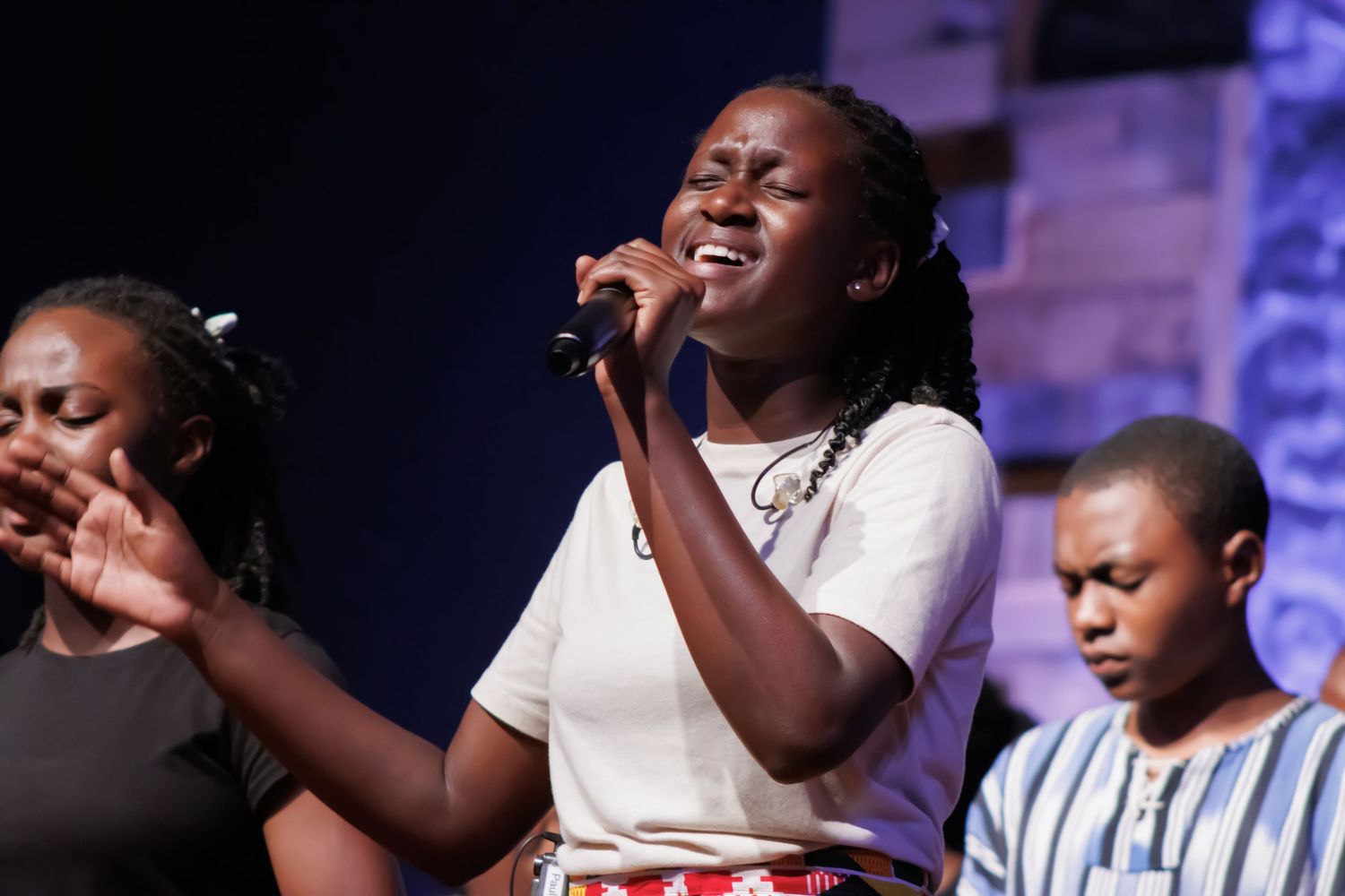 Gospel performers singing with emotional intensity under stage lights.
