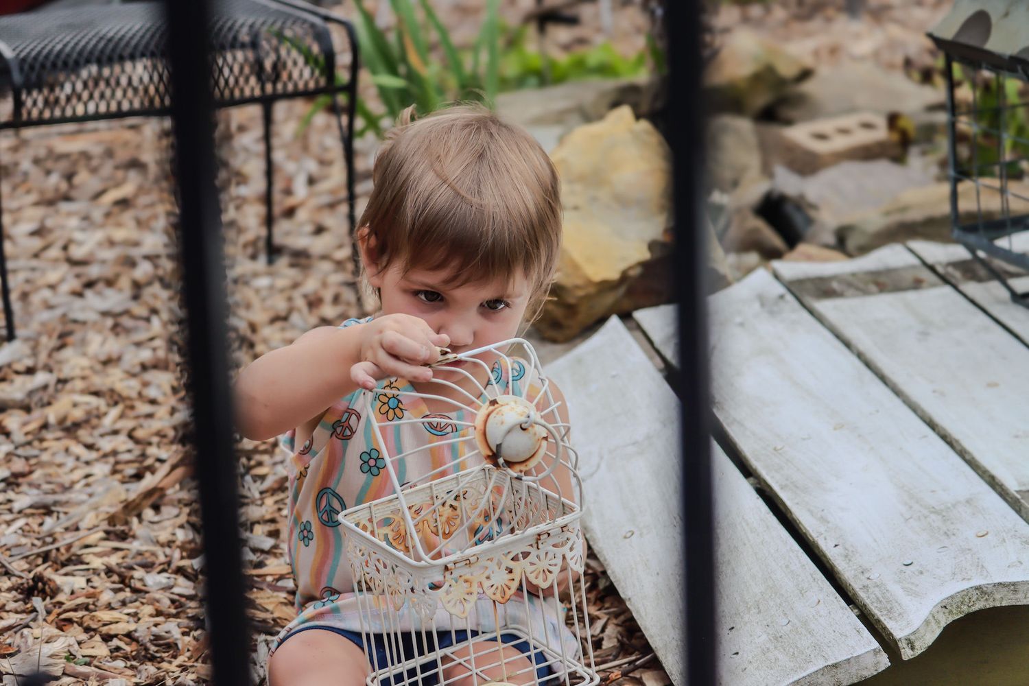 Child peeking through metal fence while playing outdoors.