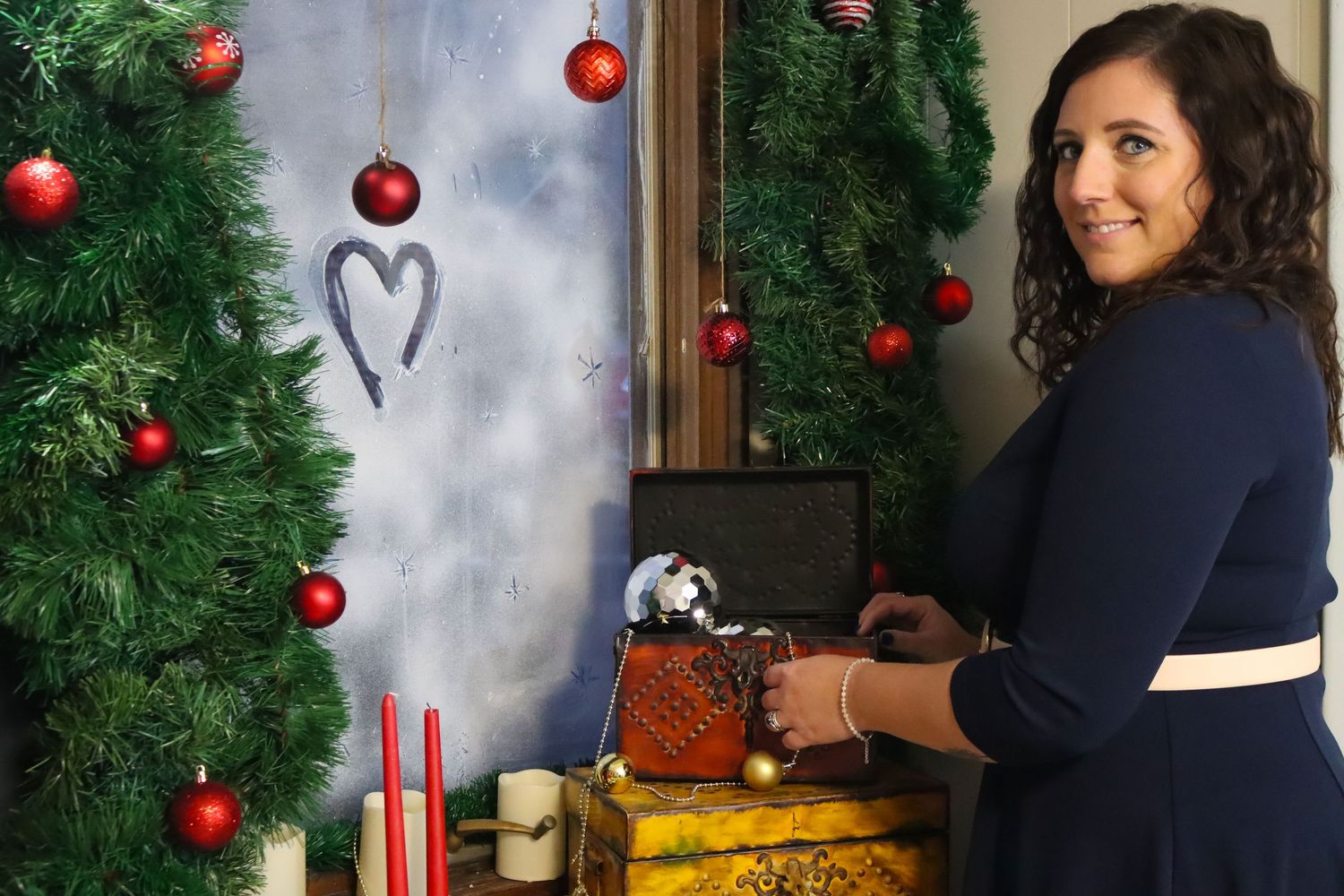 Holiday decorations featuring red ornaments and greenery against blue backdrop.