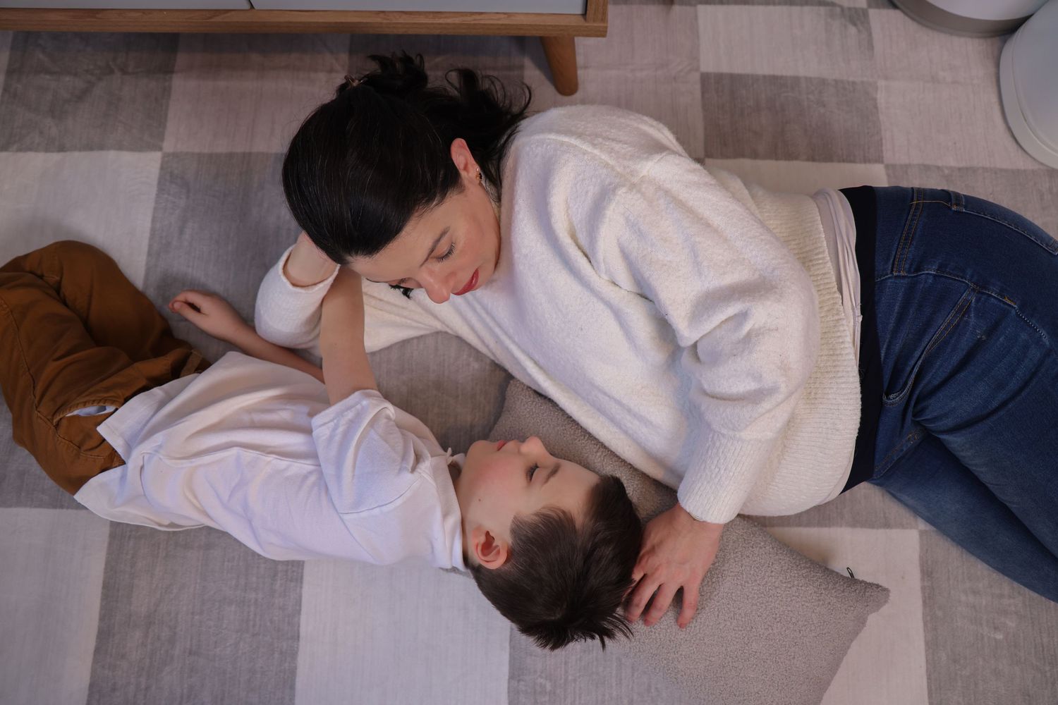 People lounging on a grey carpeted floor in casual white and blue clothing.