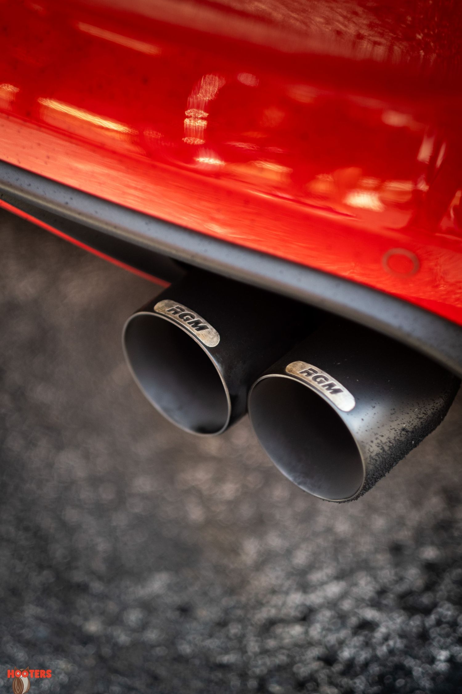 Close-up of dual black exhaust tips on a red sports car.