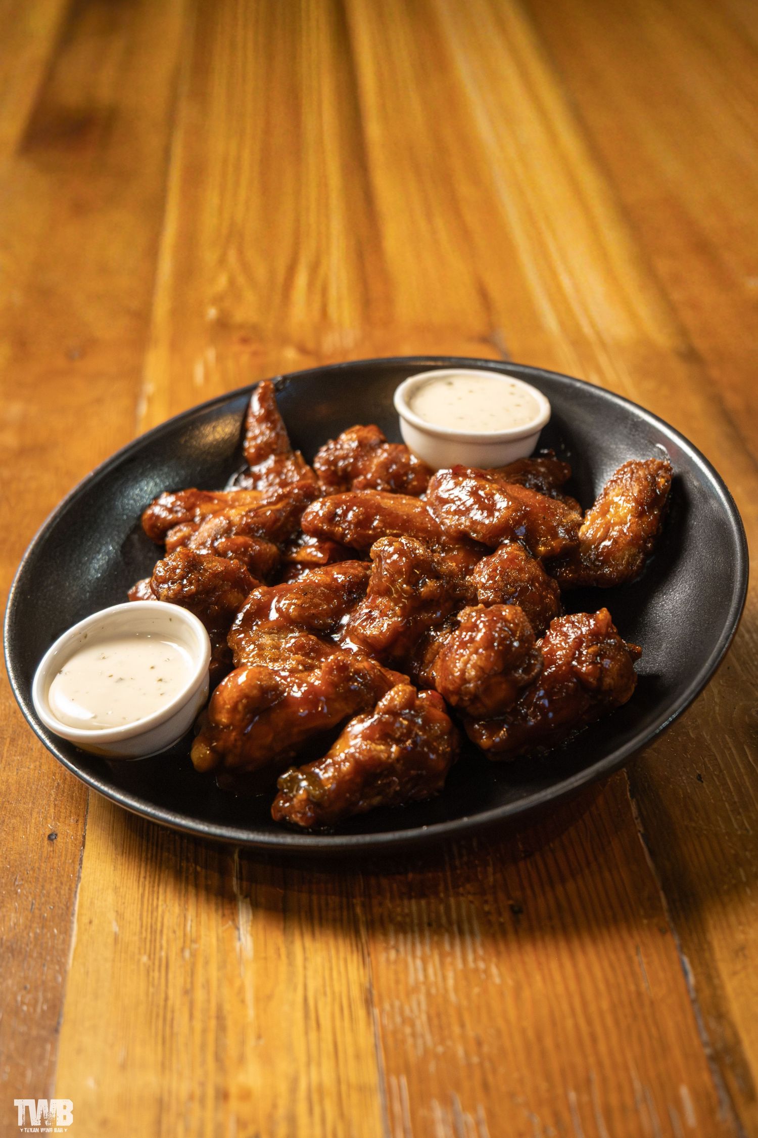 Crispy chicken wings with dipping sauce served on black plates.