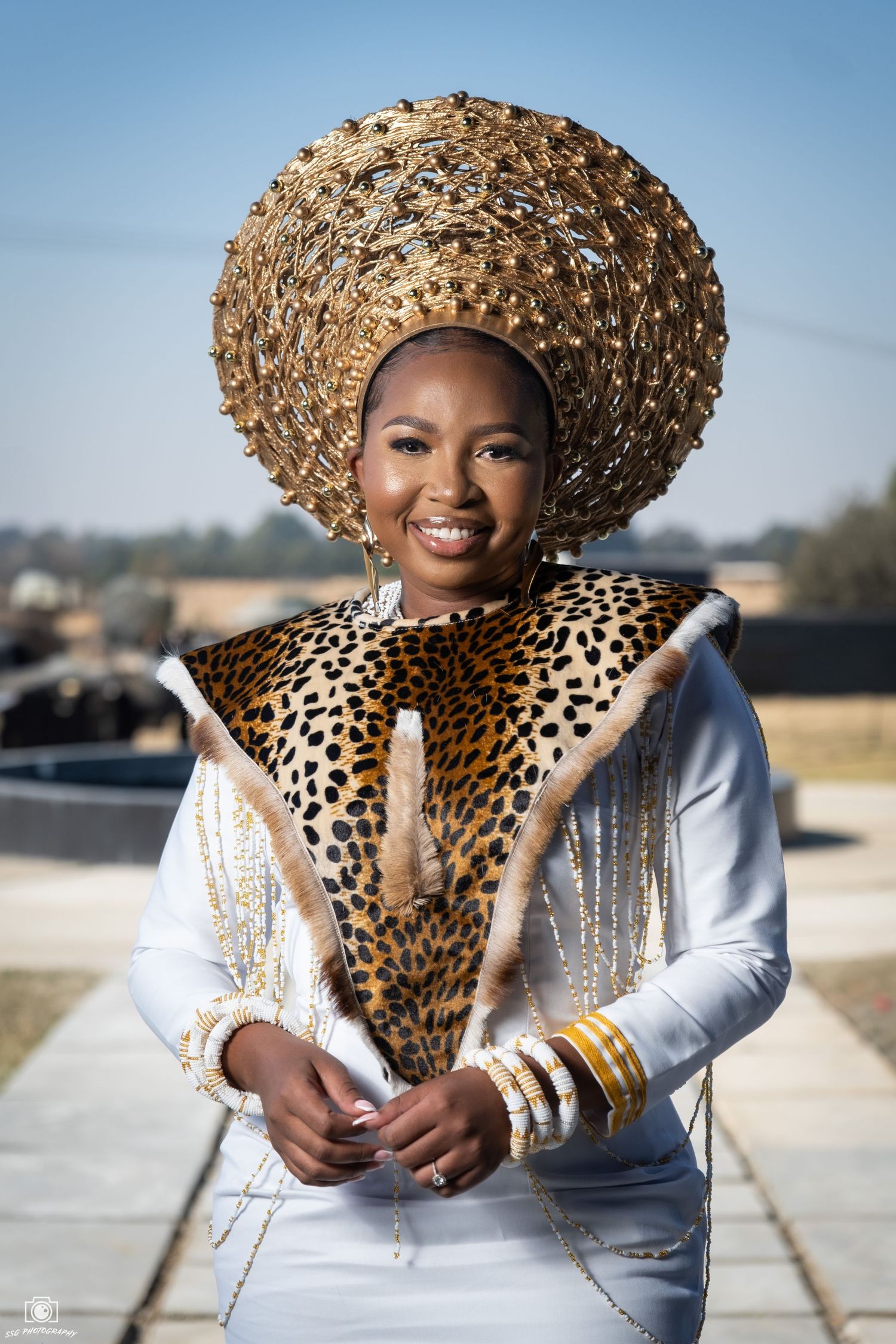 Fashion portrait featuring gold woven hat and white dress with leopard print details.