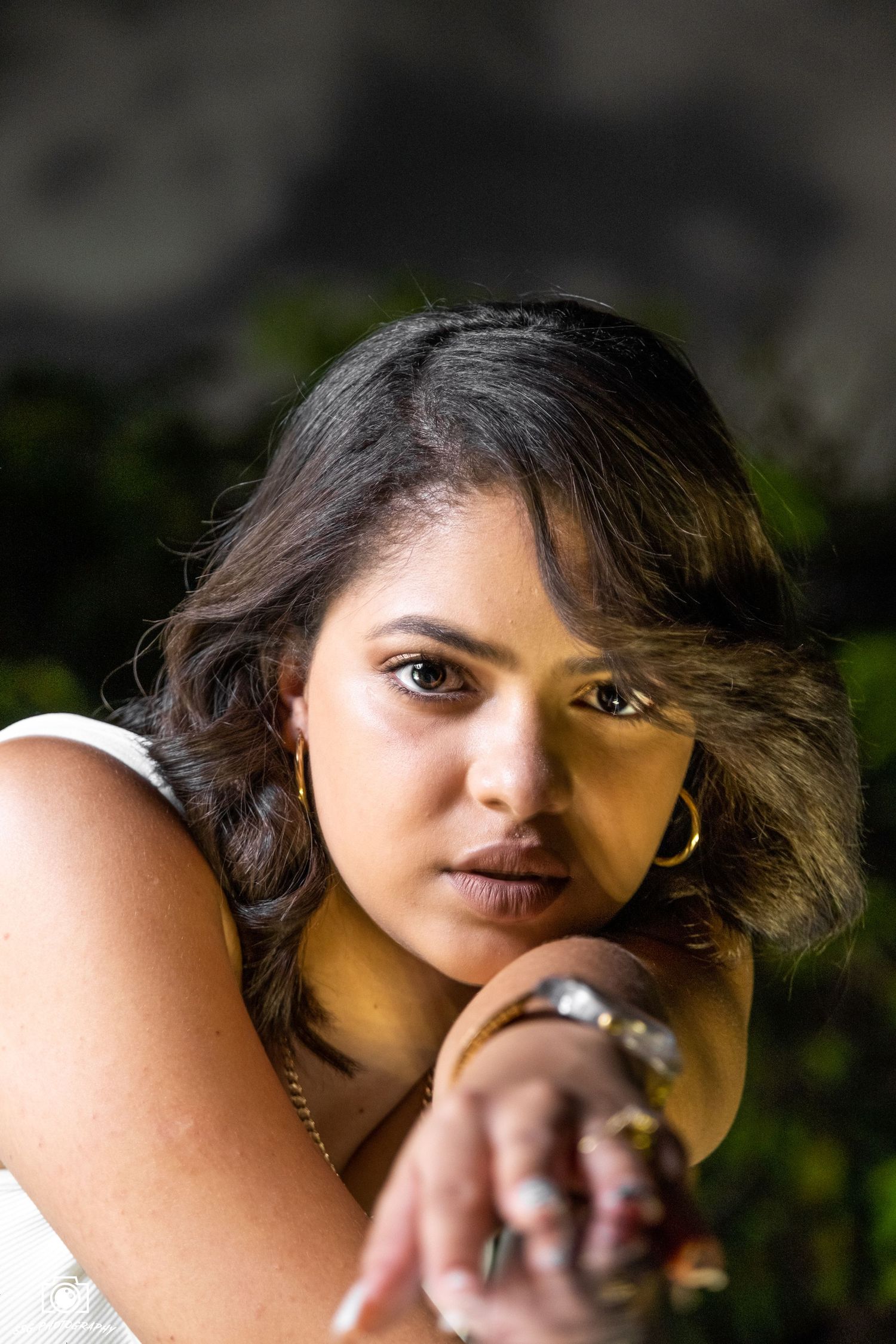 Artistic close-up portrait with dramatic side lighting and natural backdrop.