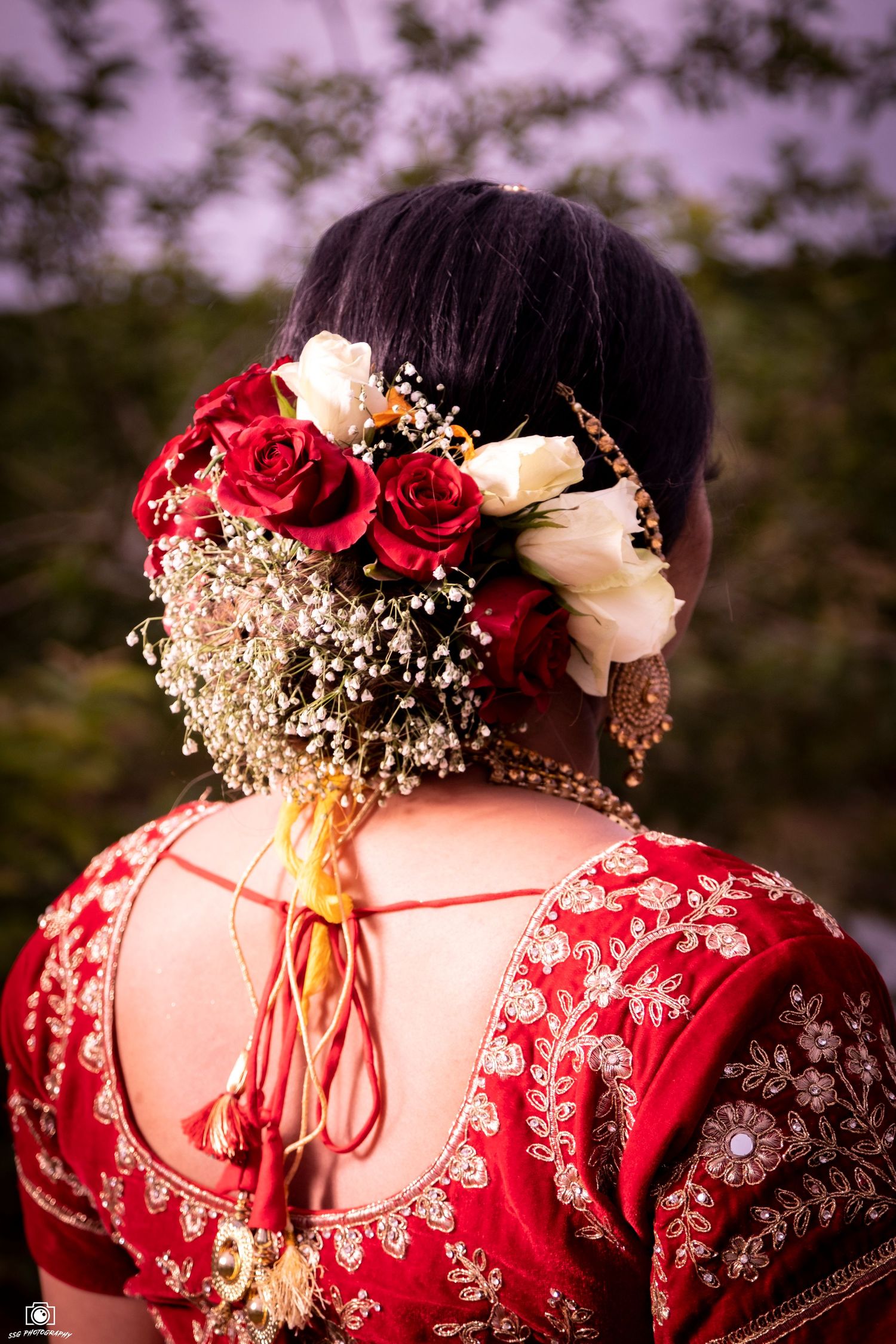 Back view of intricate red bridal dress with floral hair decoration featuring roses and baby's breath.