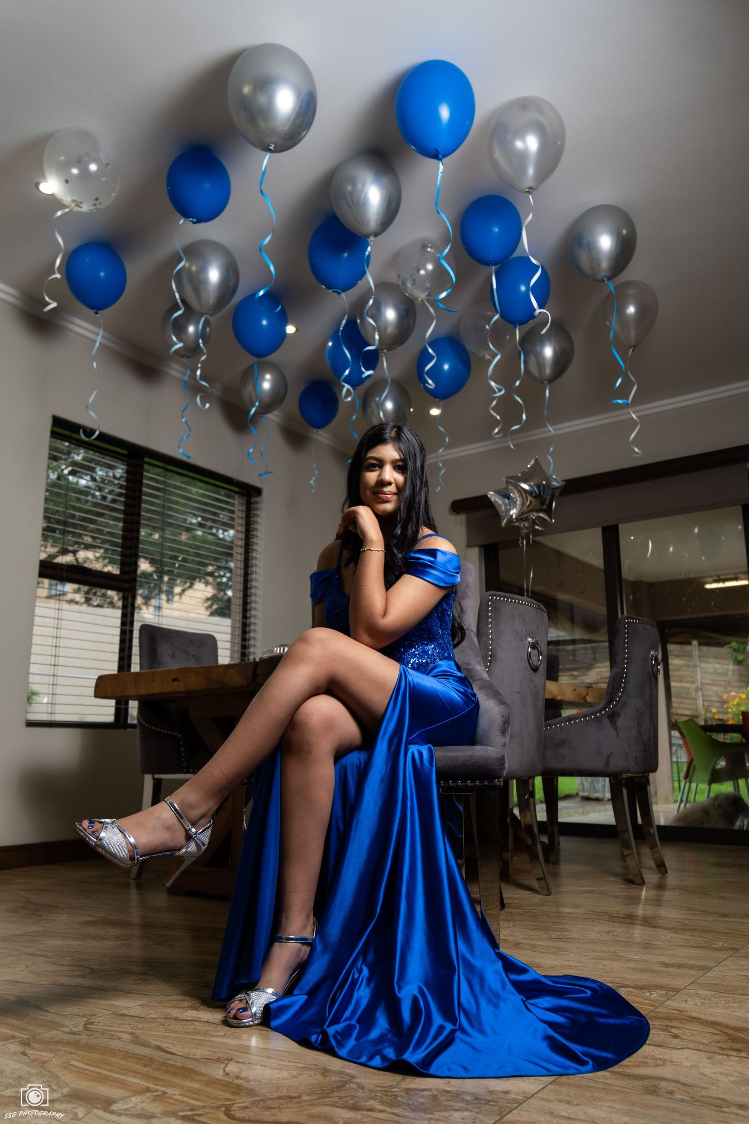 Elegant photoshoot with blue and silver balloons decorating a modern interior space.
