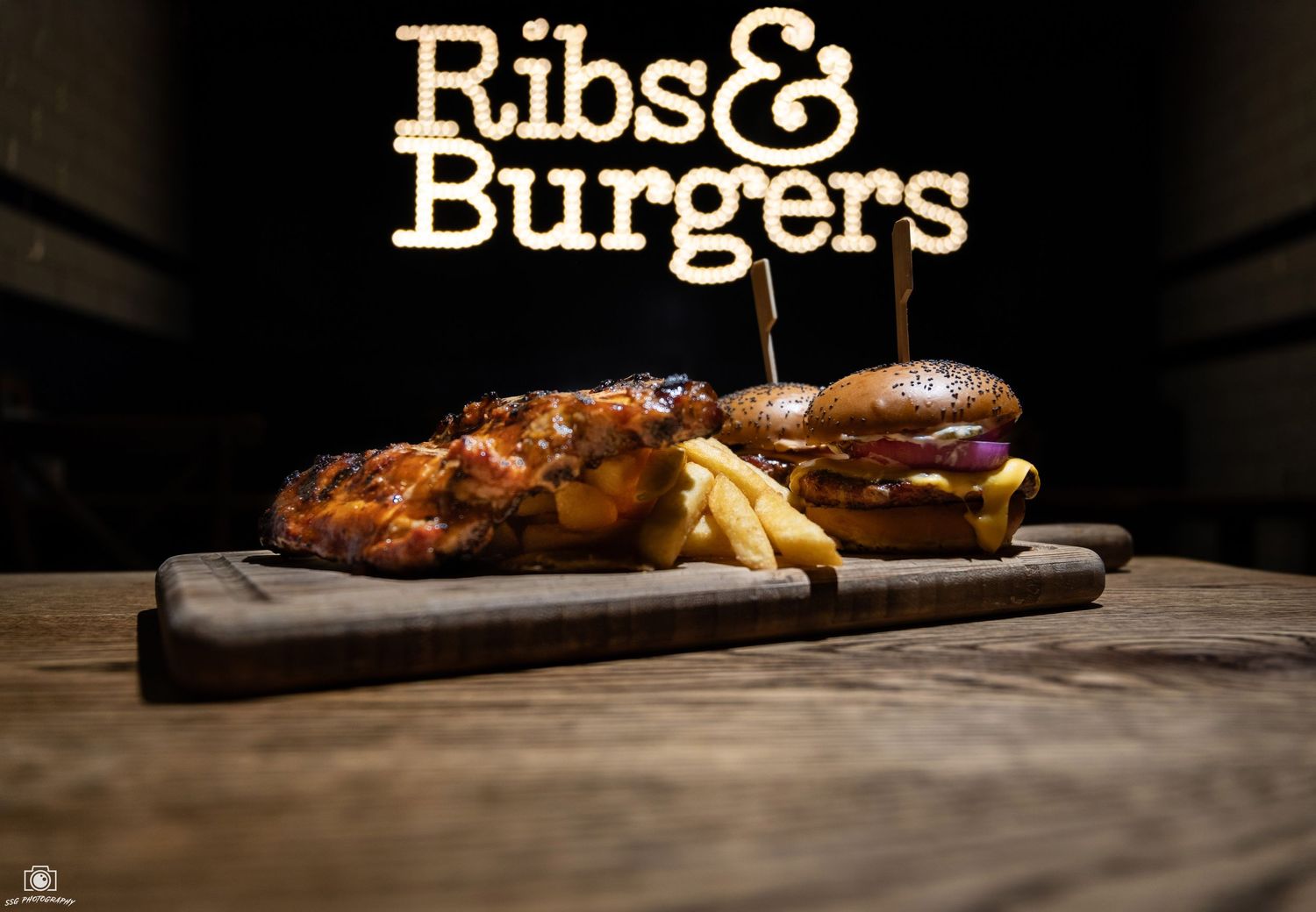 Restaurant logo design for 'Ribs & Burgers' with warm lighting and rustic atmosphere.