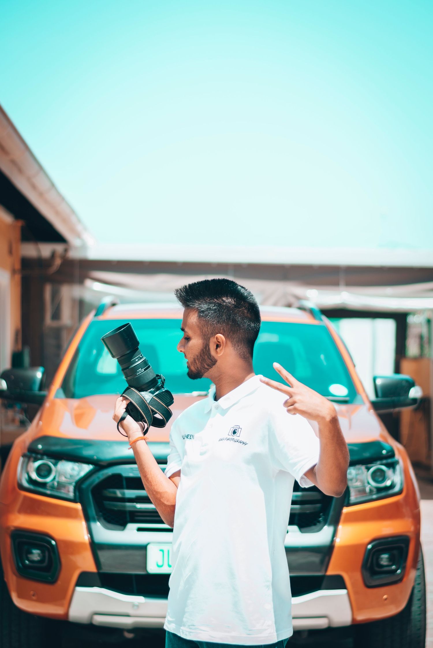 Multiple cameras being held up against a bright blue sky with vehicles visible in the background.