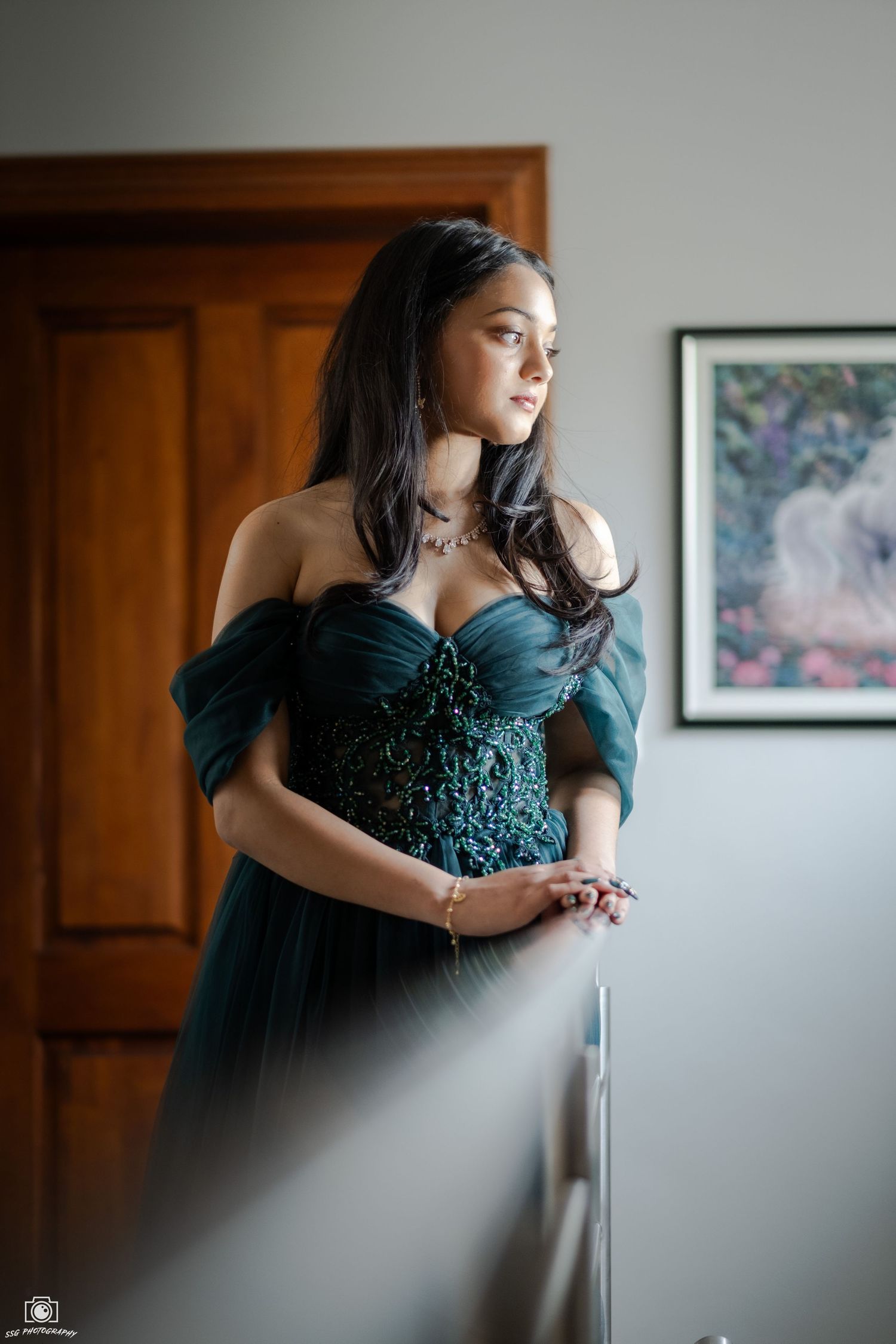 Elegant indoor portrait session featuring a dark teal formal gown against neutral walls.