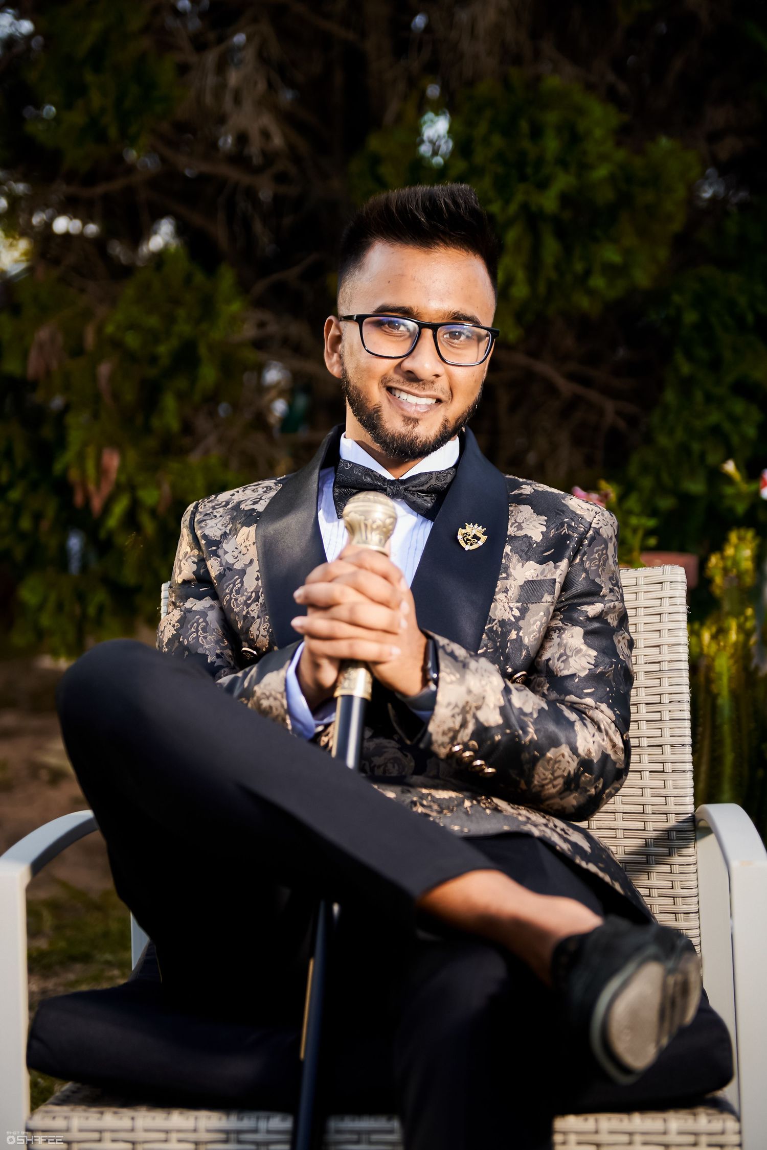 Person in formal attire with floral print blazer sitting outdoors.