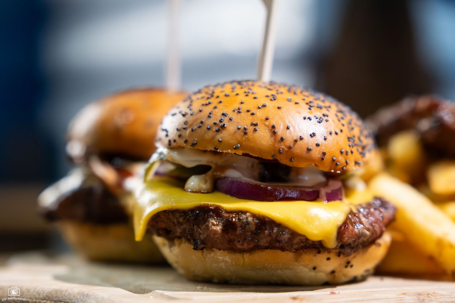 Close-up of cheeseburgers with melted cheese and sesame seed buns.