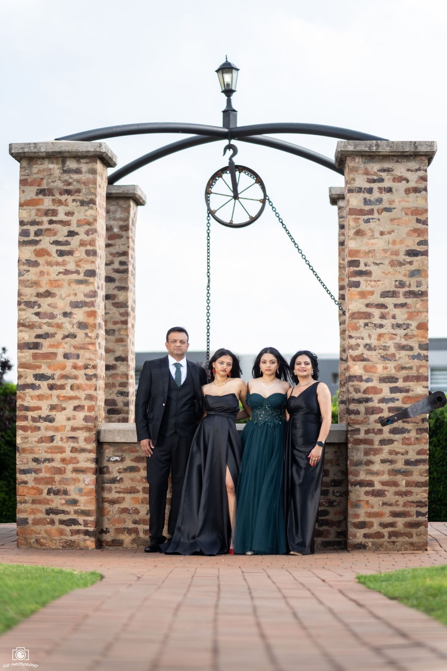 Group photo under brick archway with decorative clock and iron details.