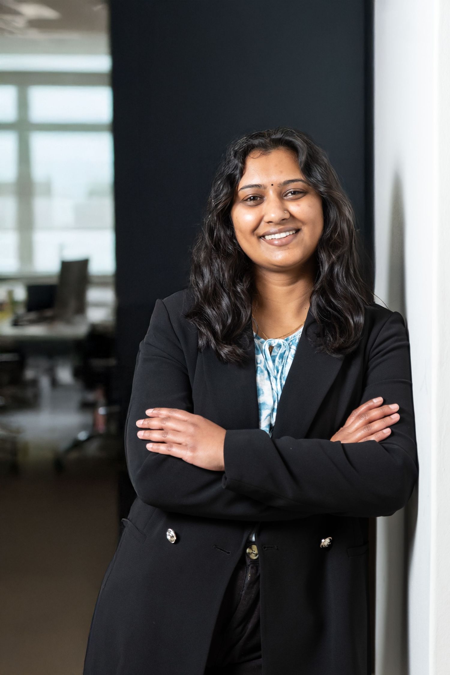 Professional portrait in business attire against a modern office background.