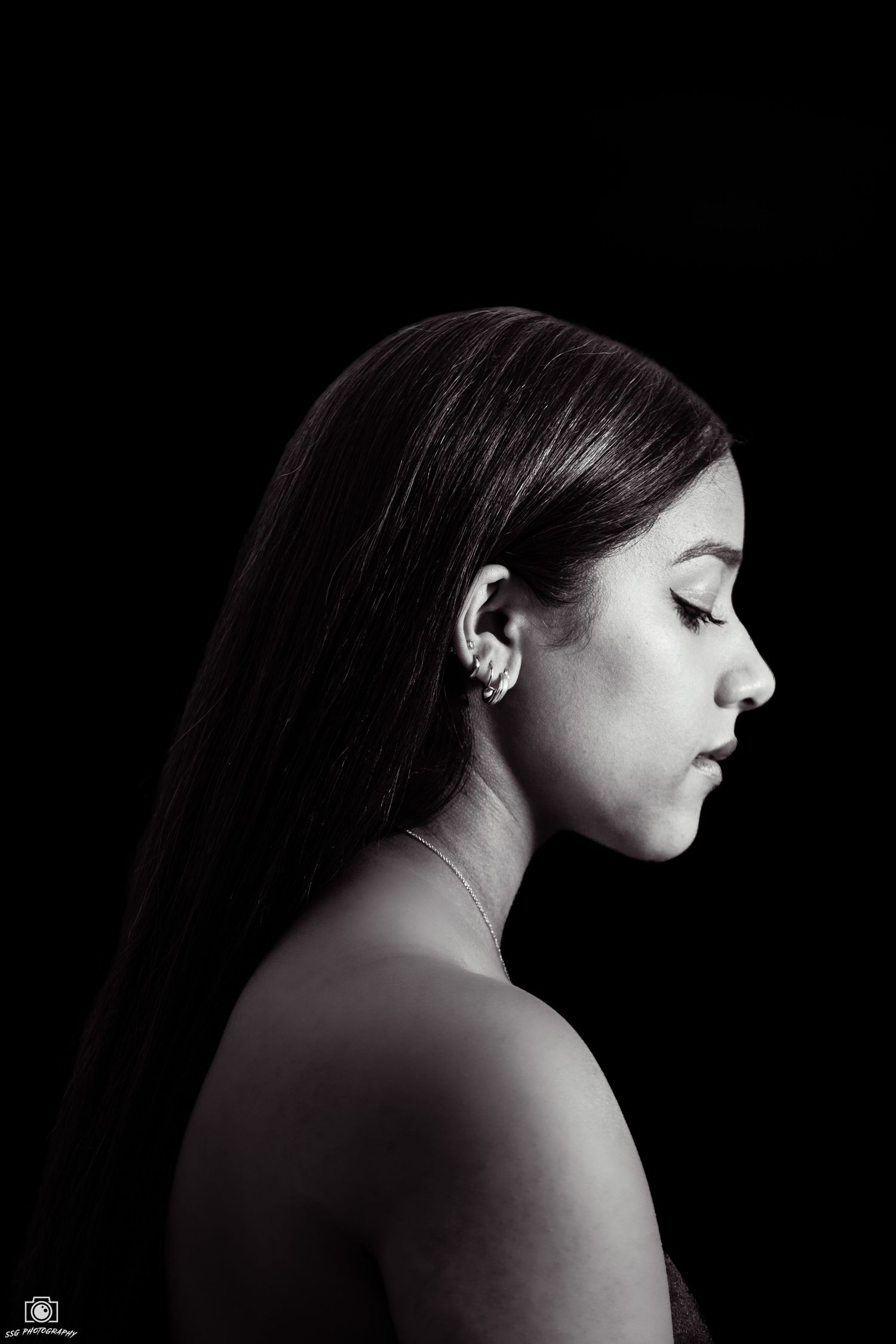 Black and white profile portrait against dark background showing elegant simplicity.