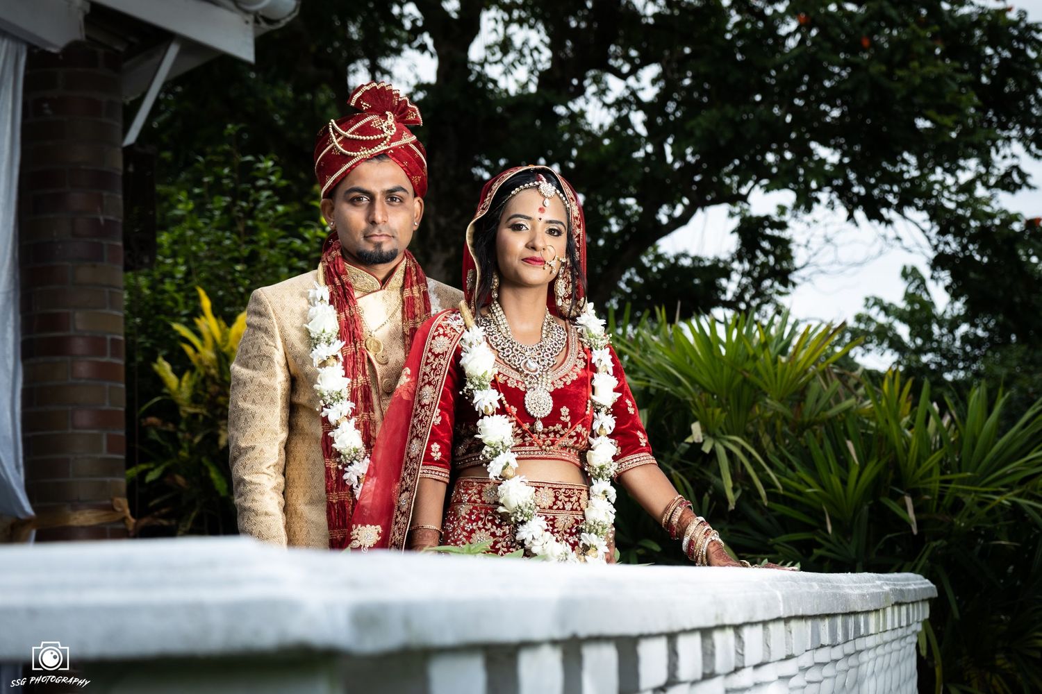 Traditional Indian wedding ceremony with couple seated outdoors.